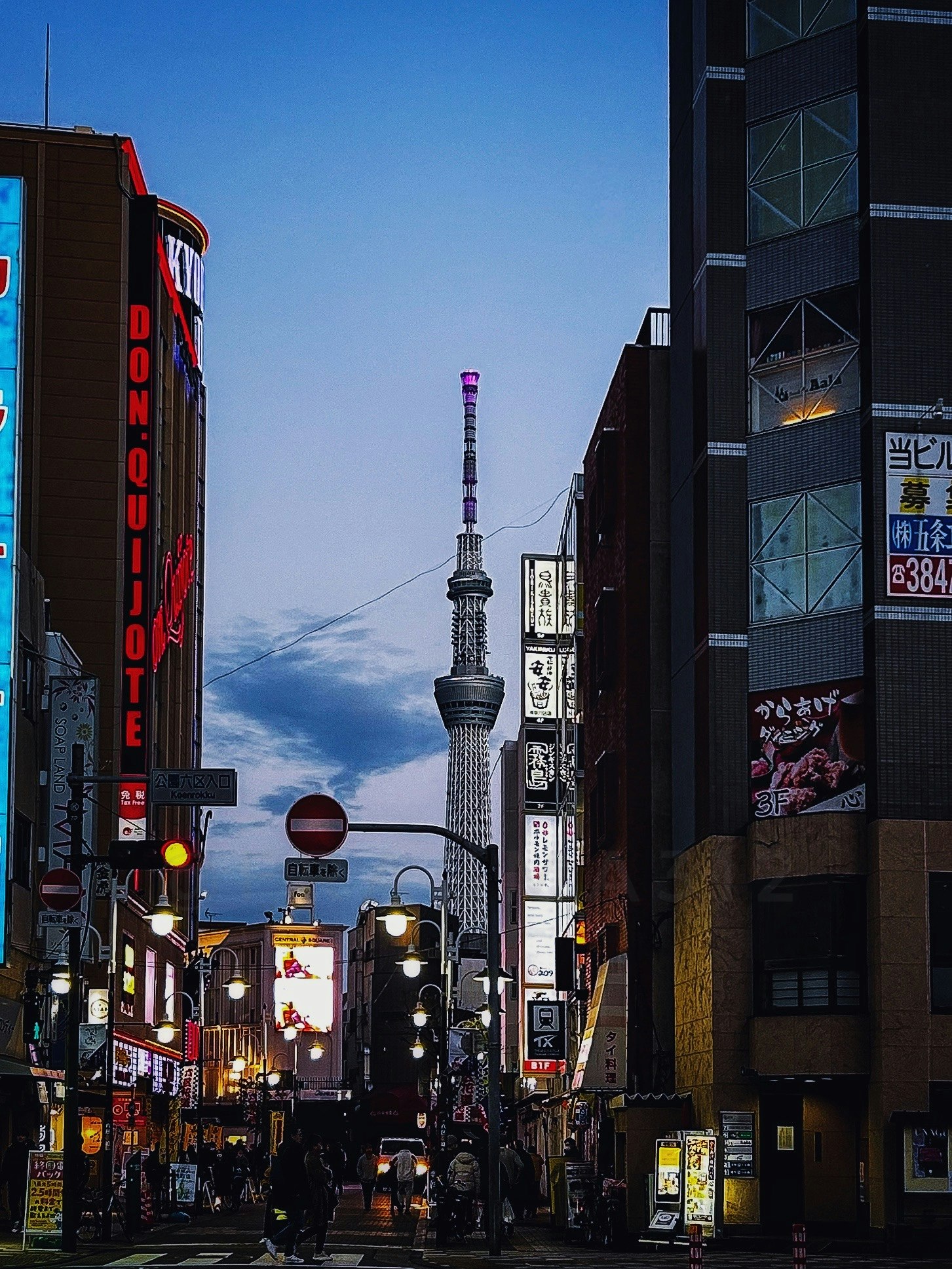 路地に立つ看板と東京スカイツリーの見える街並み