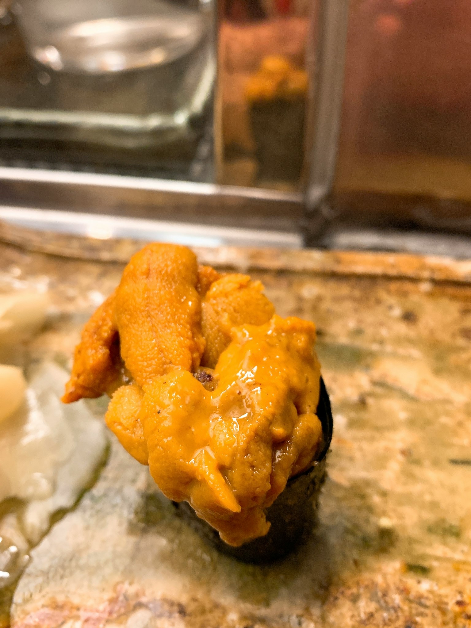 Nahaufnahme von Seeigel-Sushi, cremige, lebendige orange Farbe, auf Algen ruhend