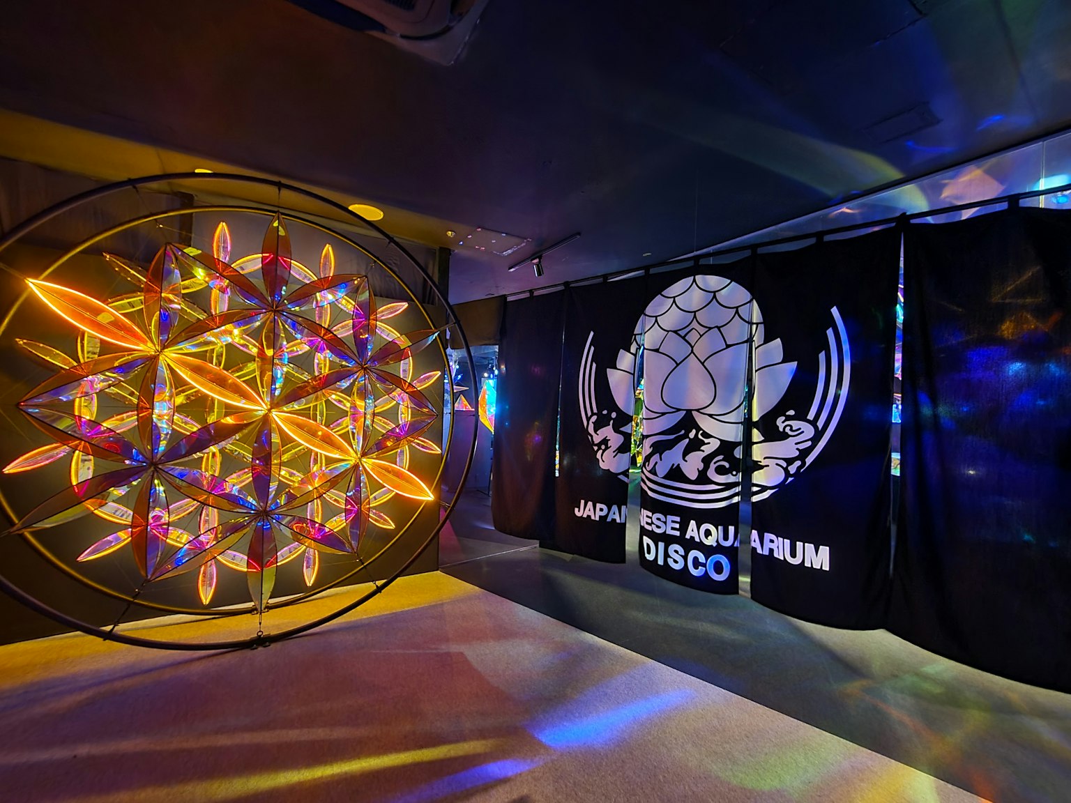 Scène intérieure avec une installation artistique lumineuse colorée et une grande bannière