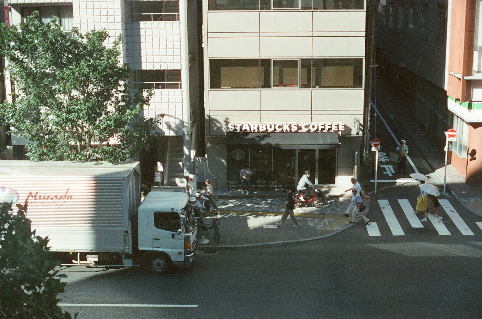 Städtische Szene mit einem Starbucks-Schild und einem Lkw, der die Straße überquert