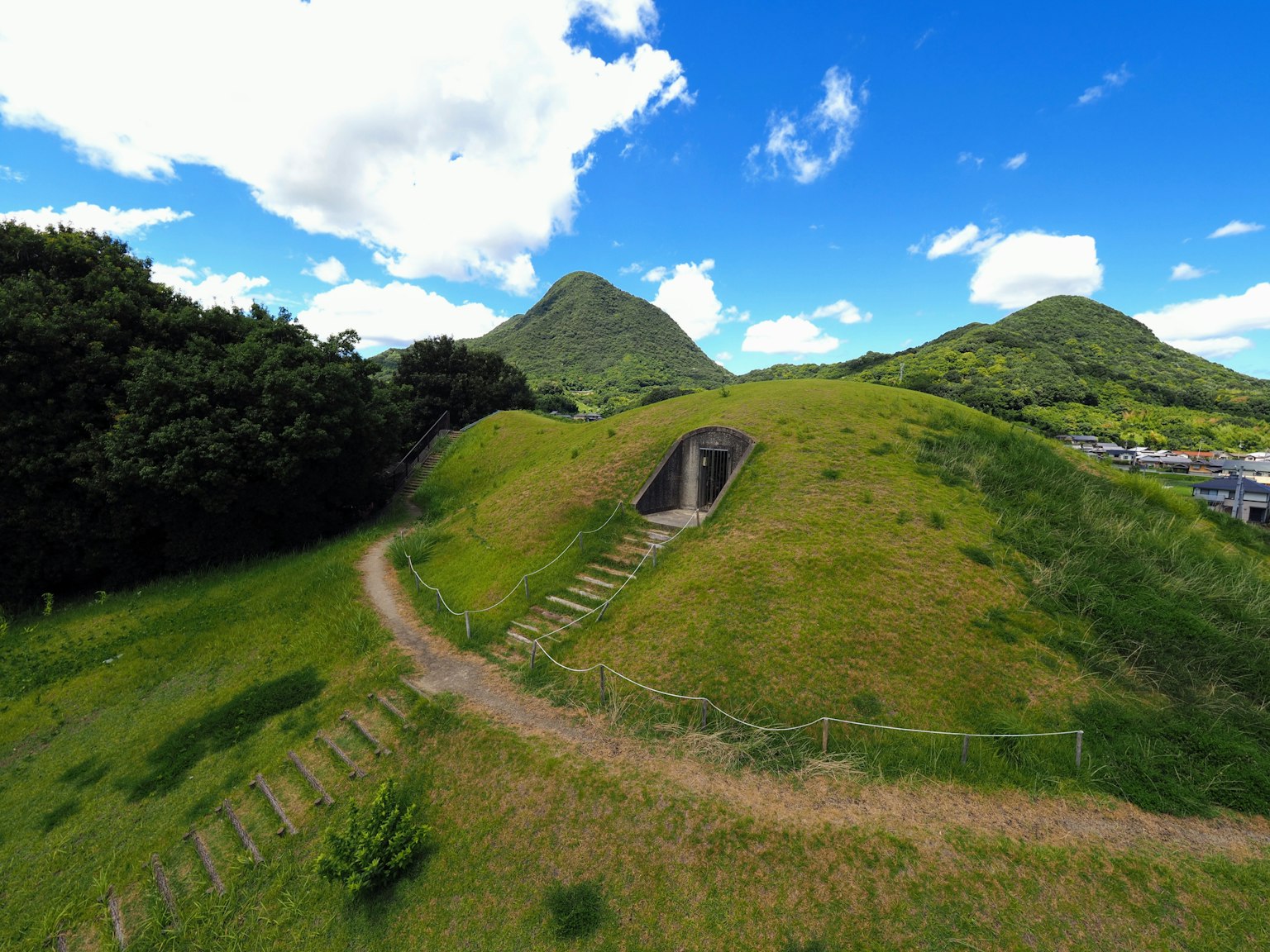 Paisaje de un antiguo túmulo bajo colinas verdes y cielo azul