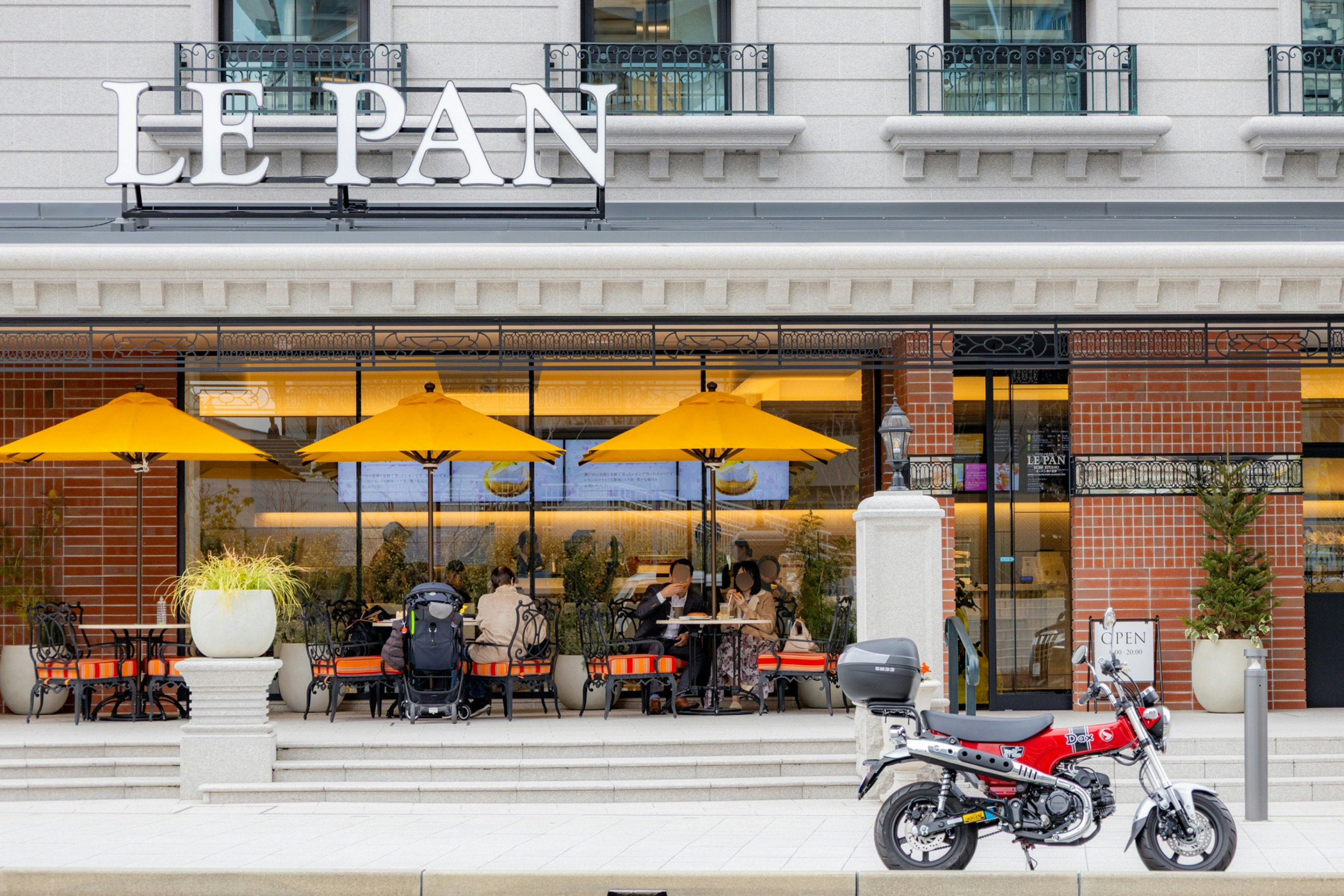 オレンジの傘とバイクが並ぶベーカリーの店先