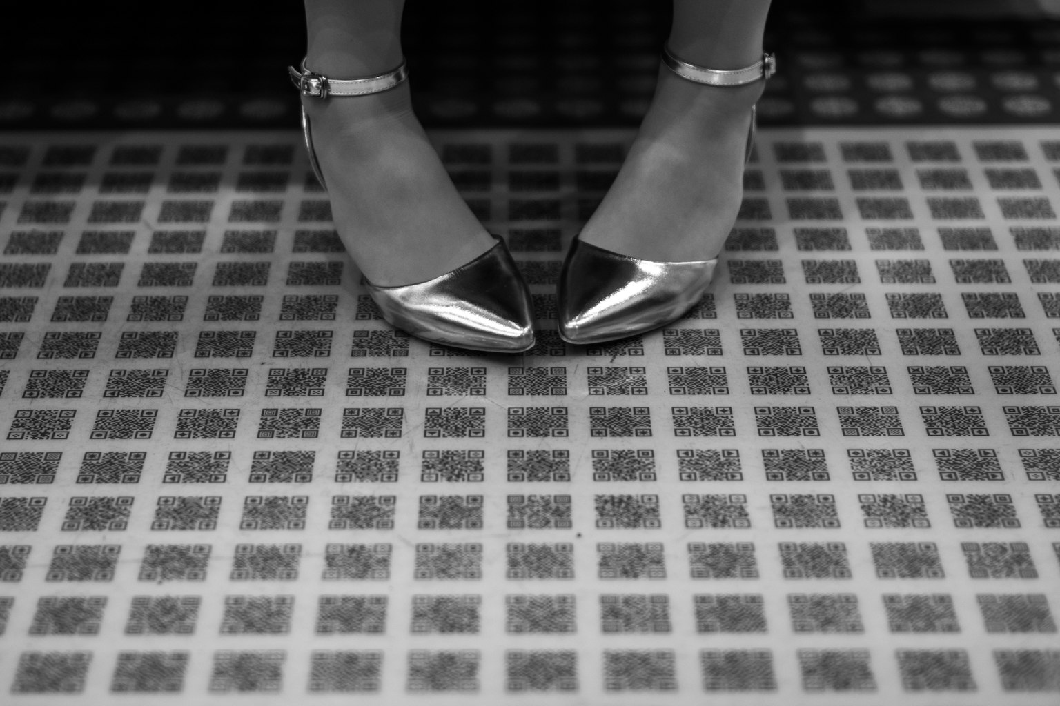 Zapatos de tacón negros y plateados sobre un suelo de baldosas