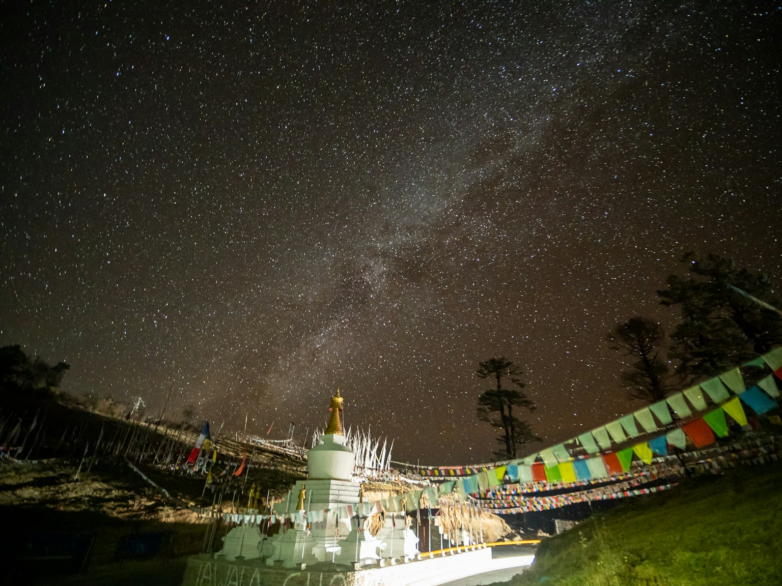 Vista di una stupa sotto un cielo stellato con bandiere di preghiera colorate