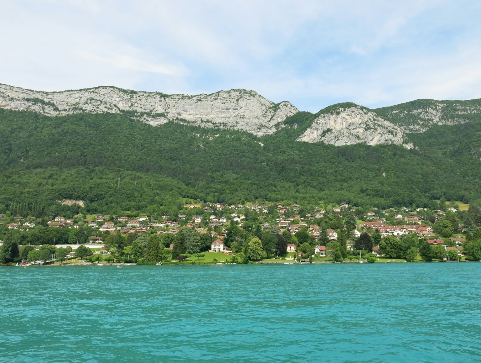 Scenic view of a turquoise lake with lush green mountains and a quaint village