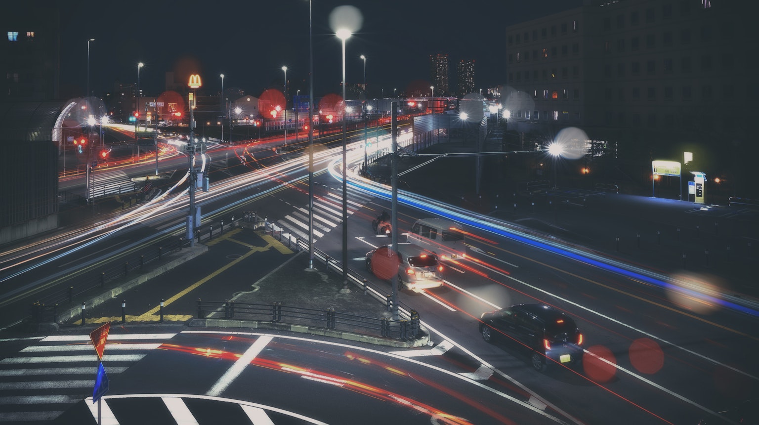 Light trails of cars at a busy intersection at night with streetlights