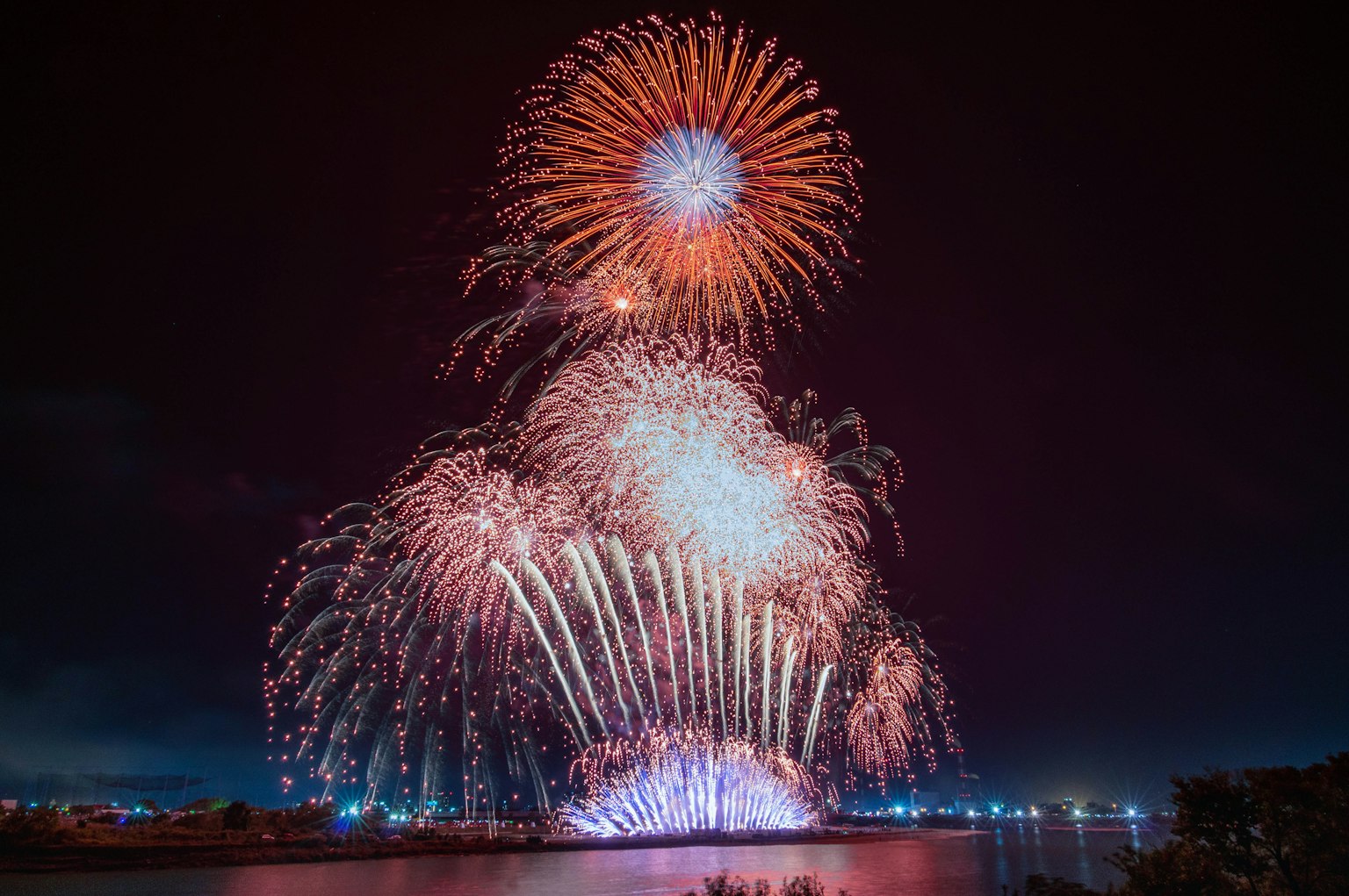 五彩缤纷的烟花在宁静的水面上绽放于夜空