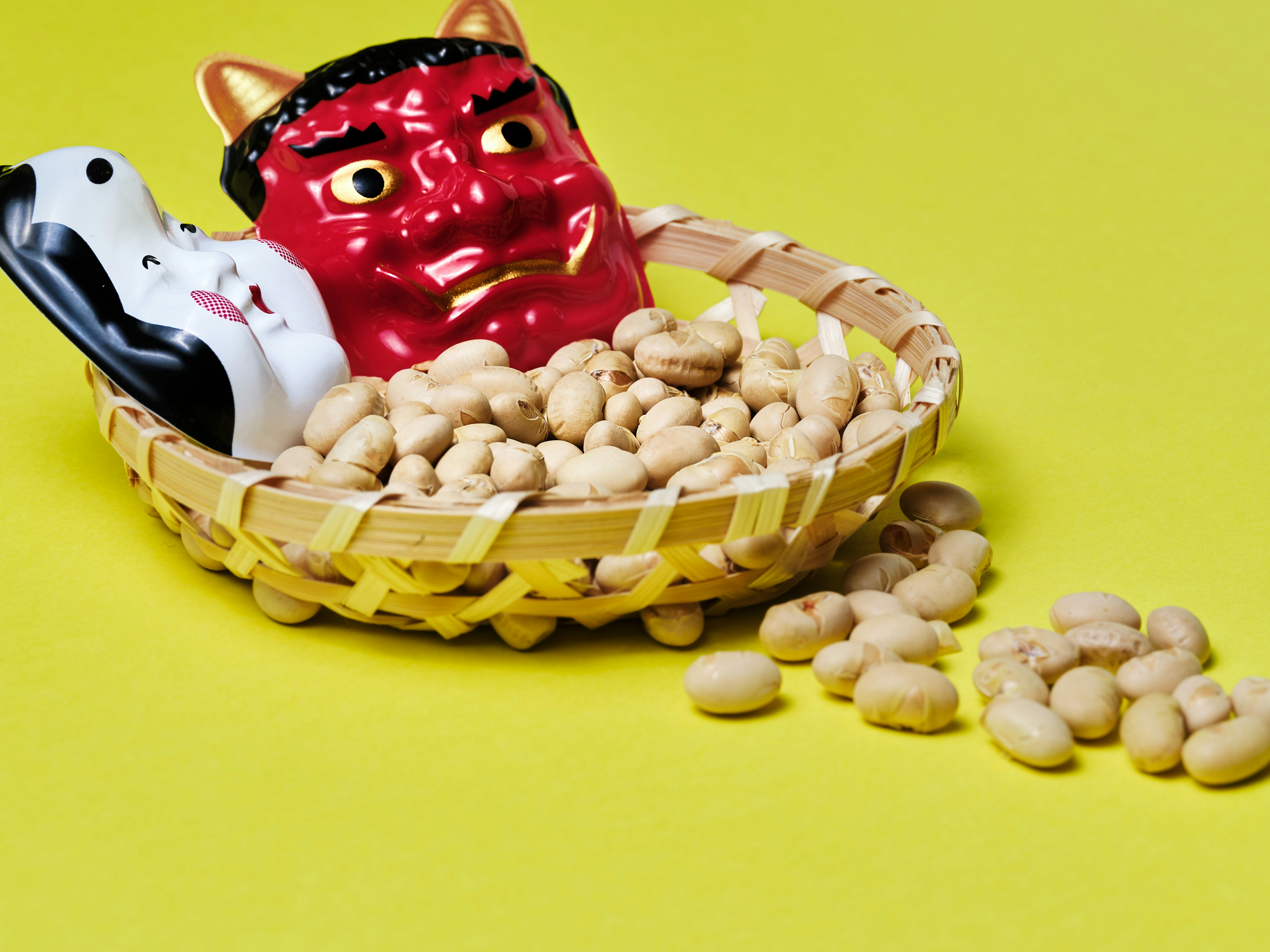 赤い招き猫の置物と豆の入った竹かご