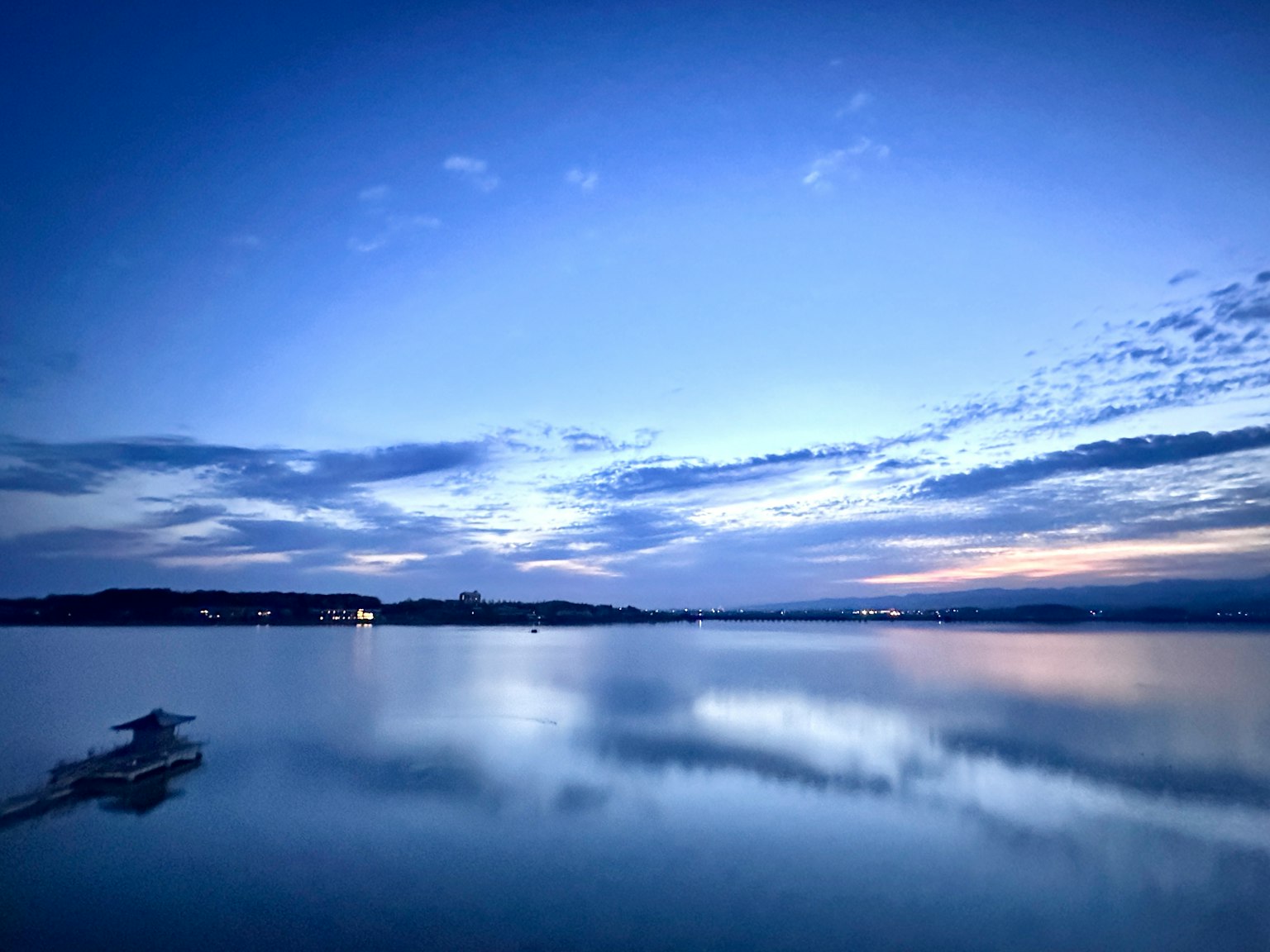 Vista pittoresca di un lago tranquillo sotto un cielo azzurro con nuvole riflettenti