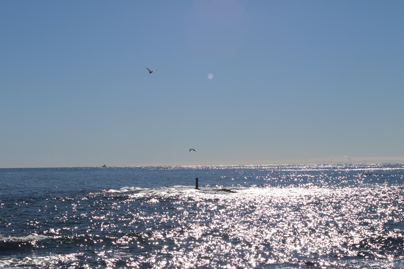 Lumière du soleil se reflétant sur des eaux océaniques calmes avec des bateaux au loin
