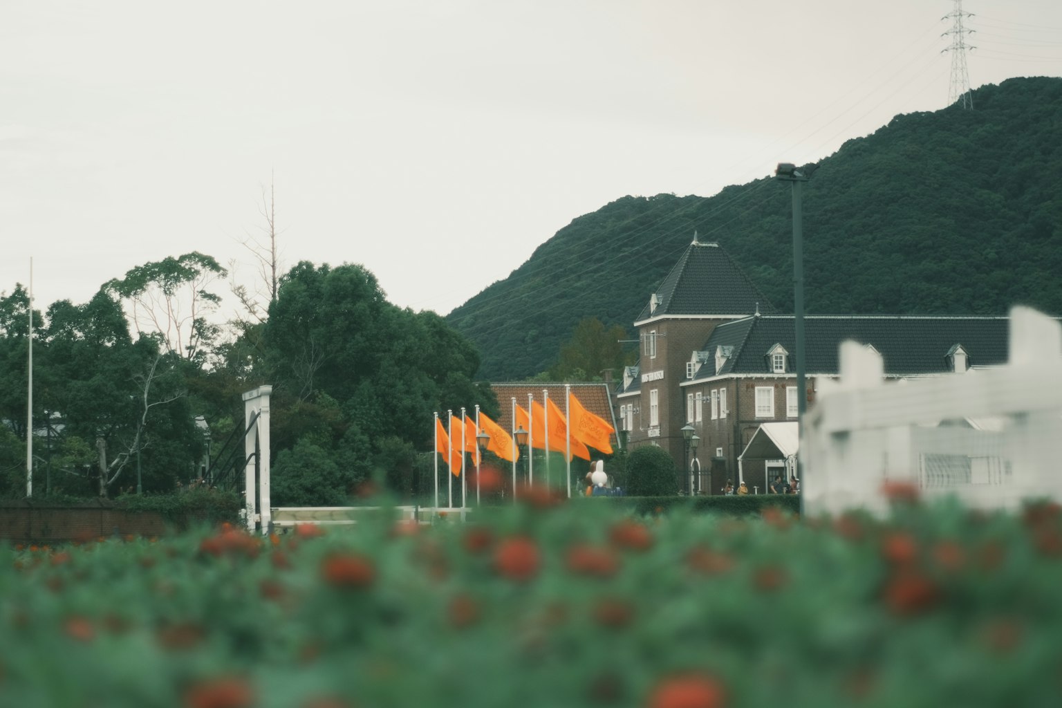 Paysage avec des drapeaux orange et un bâtiment blanc avec une montagne verte en arrière-plan