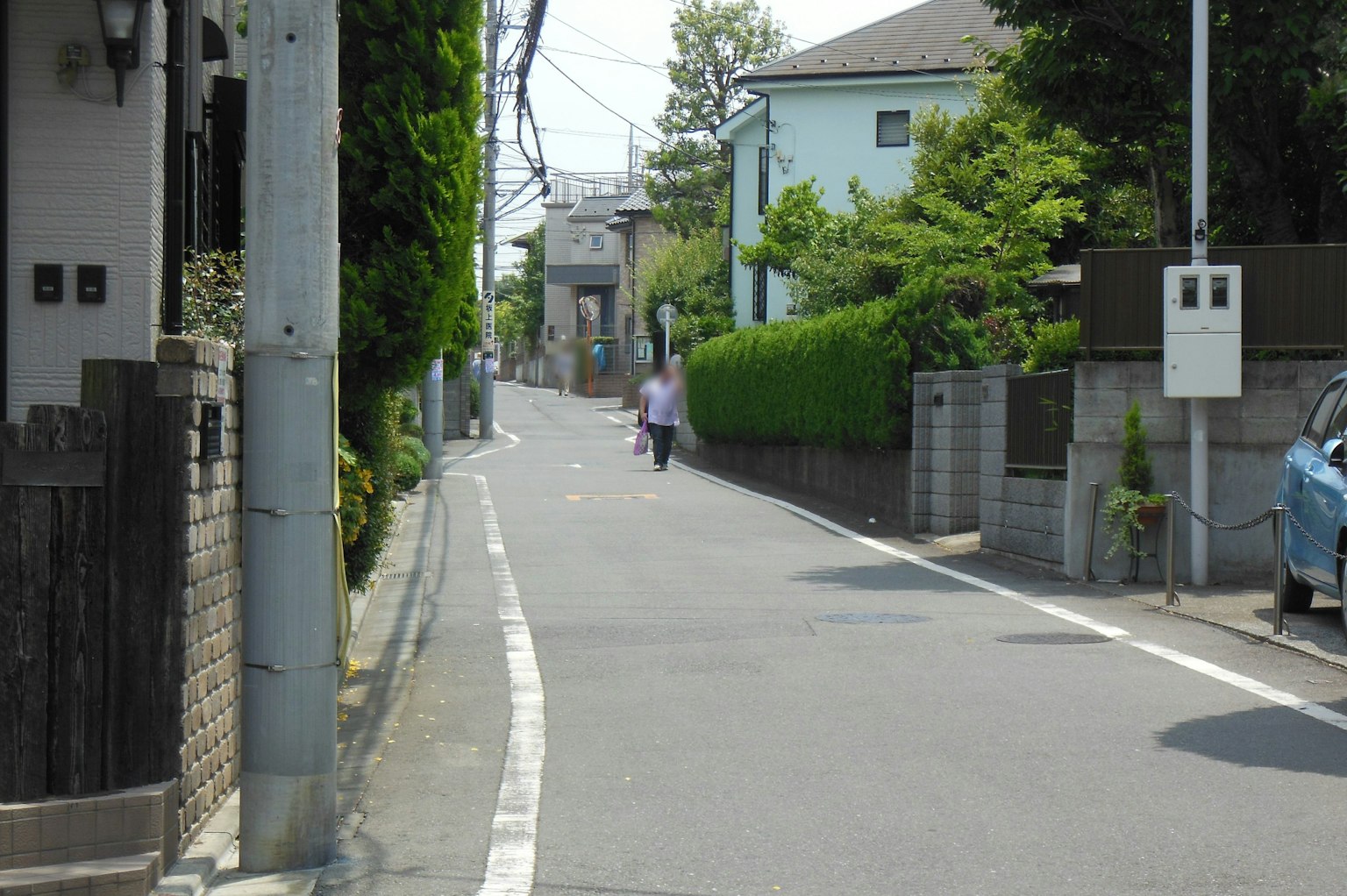 Quiet residential street in Japan with green trees and houses