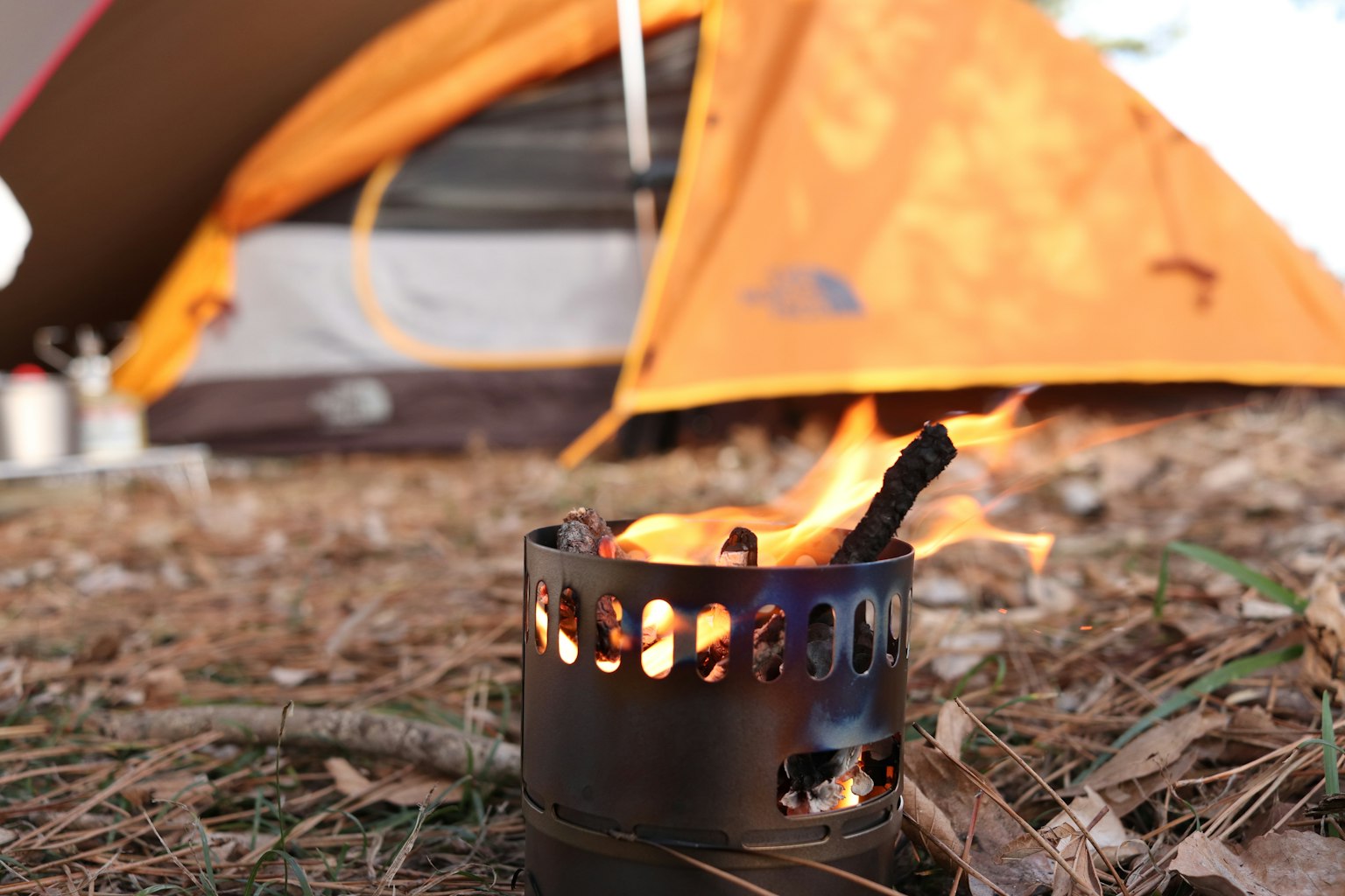 Tenda camping oranye dengan nyala kompor kecil