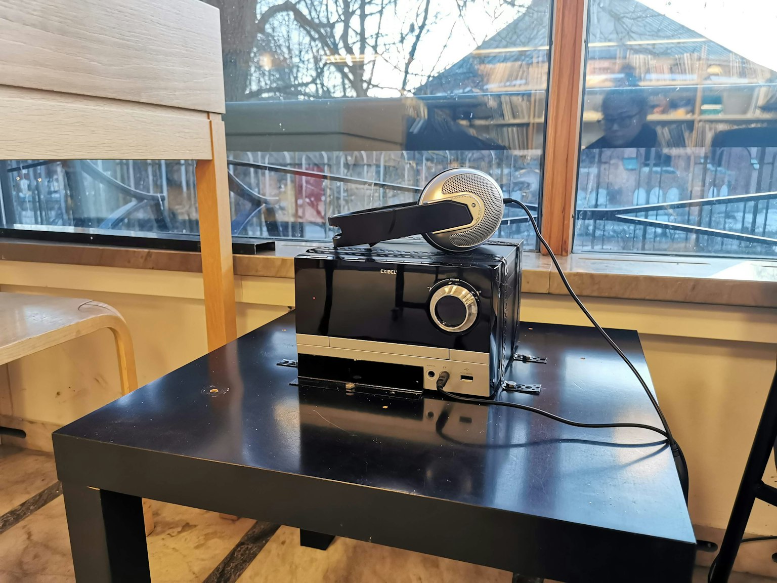Ein Projektor und Kopfhörer auf einem Tisch neben einem Fenster mit Aussicht