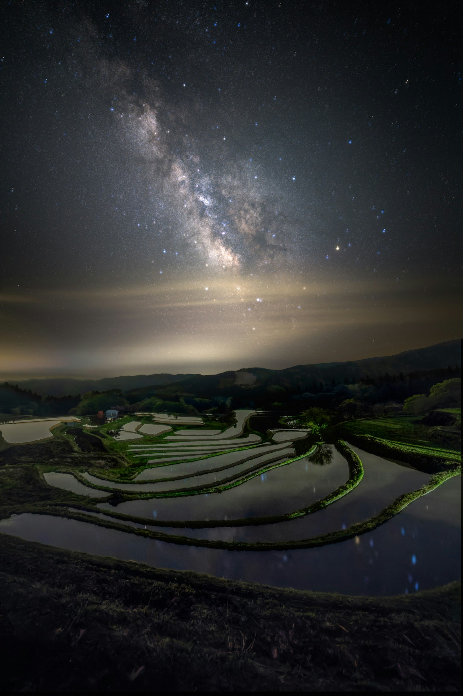夜空に広がる天の川と田園の曲がりくねった道の風景