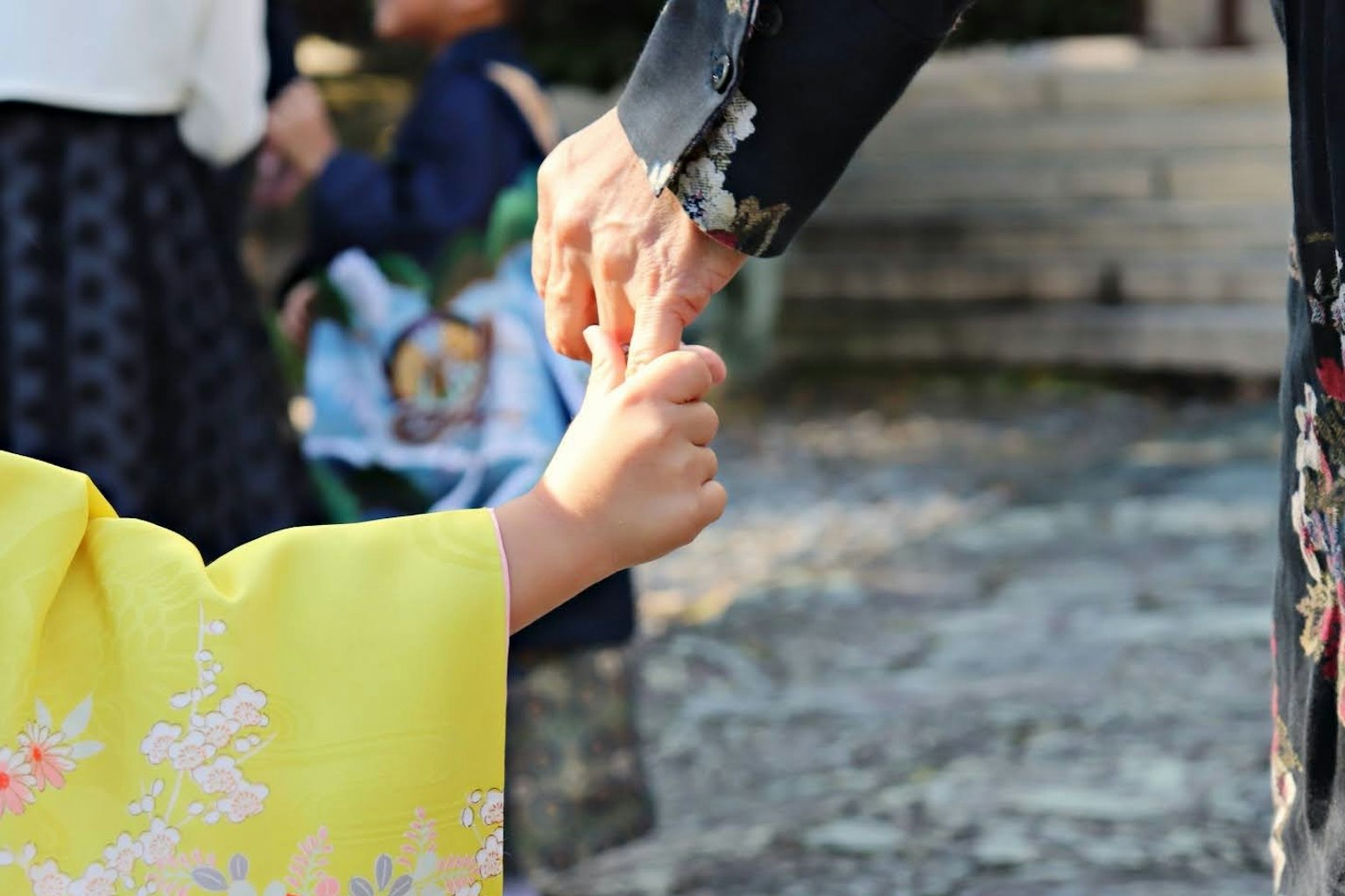 Trẻ em trong kimono màu vàng nắm tay người lớn