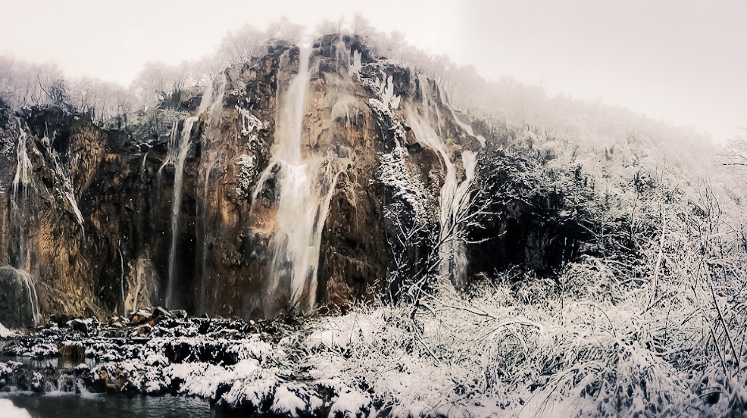被雪覆盖的瀑布从岩石悬崖上流下