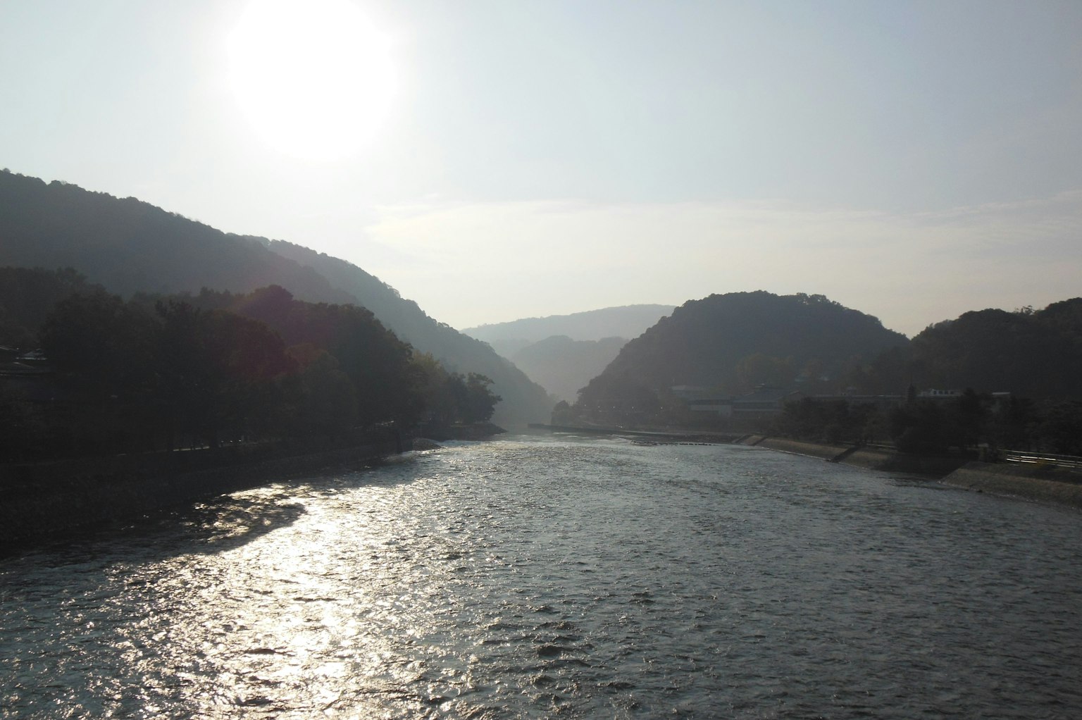 Fluss, der durch Berge fließt, mit Sonnenlicht, das auf das Wasser reflektiert