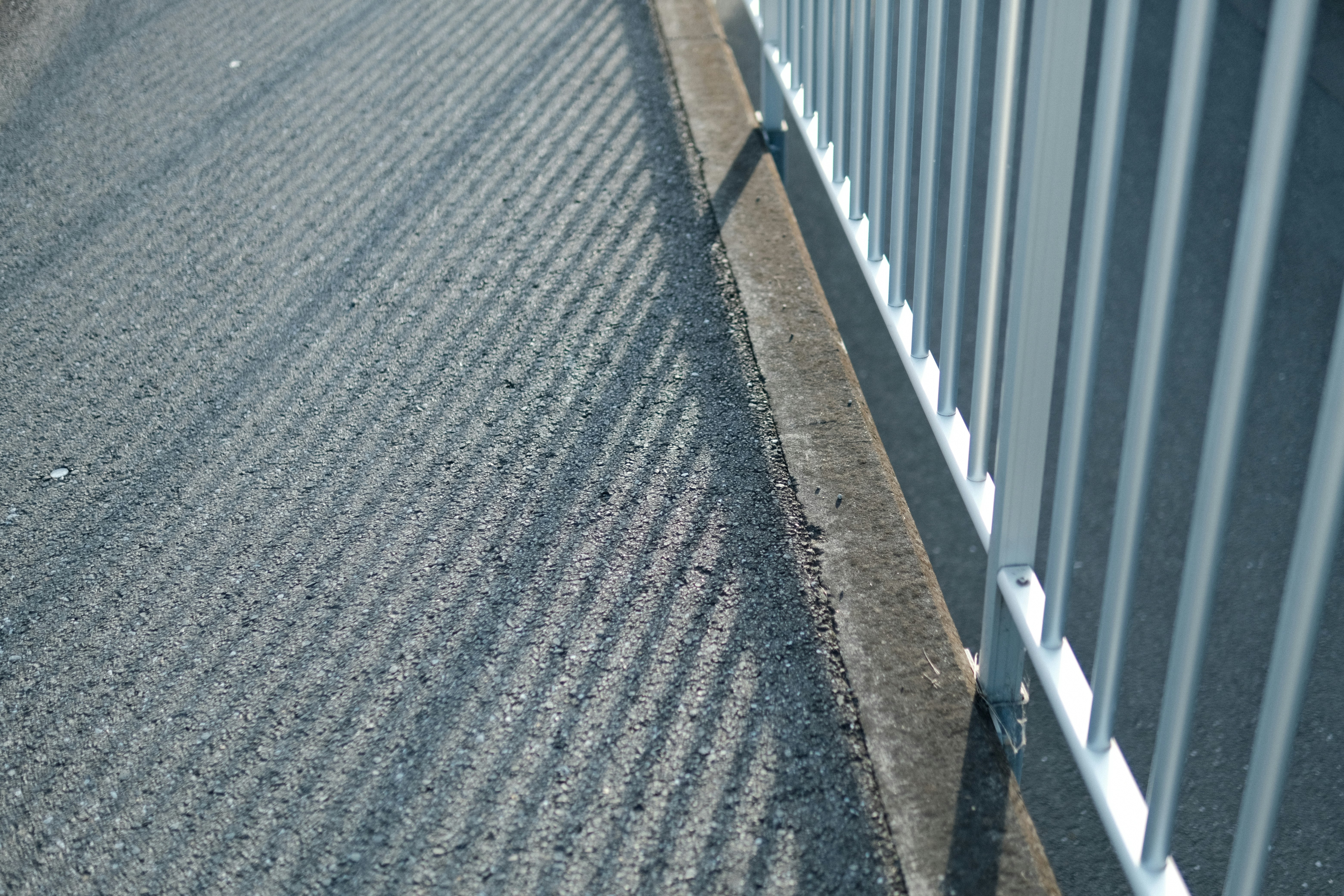 金属フェンス沿いのコンクリート歩道の質感
