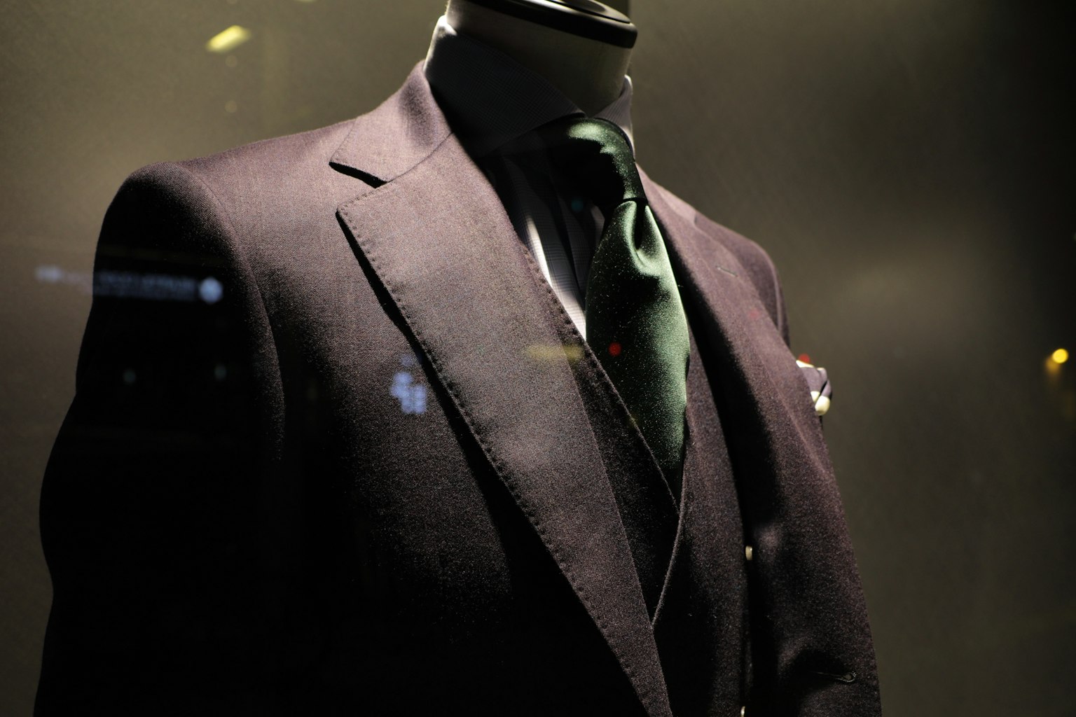 Traje elegante exhibido en un entorno oscuro con una corbata verde