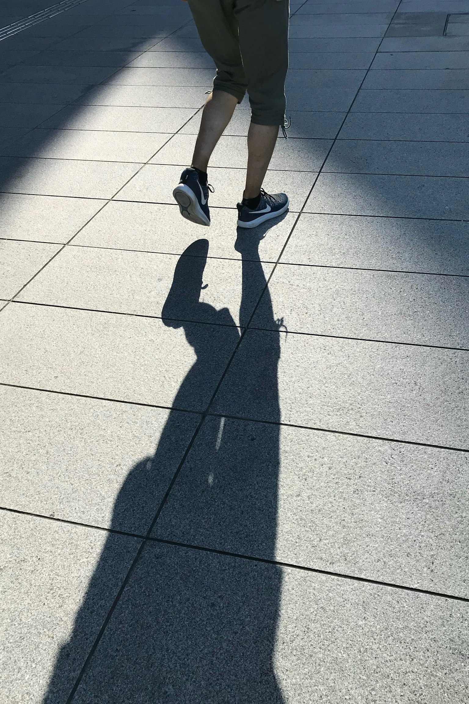 L'ombre d'une personne marchant sur le pavé