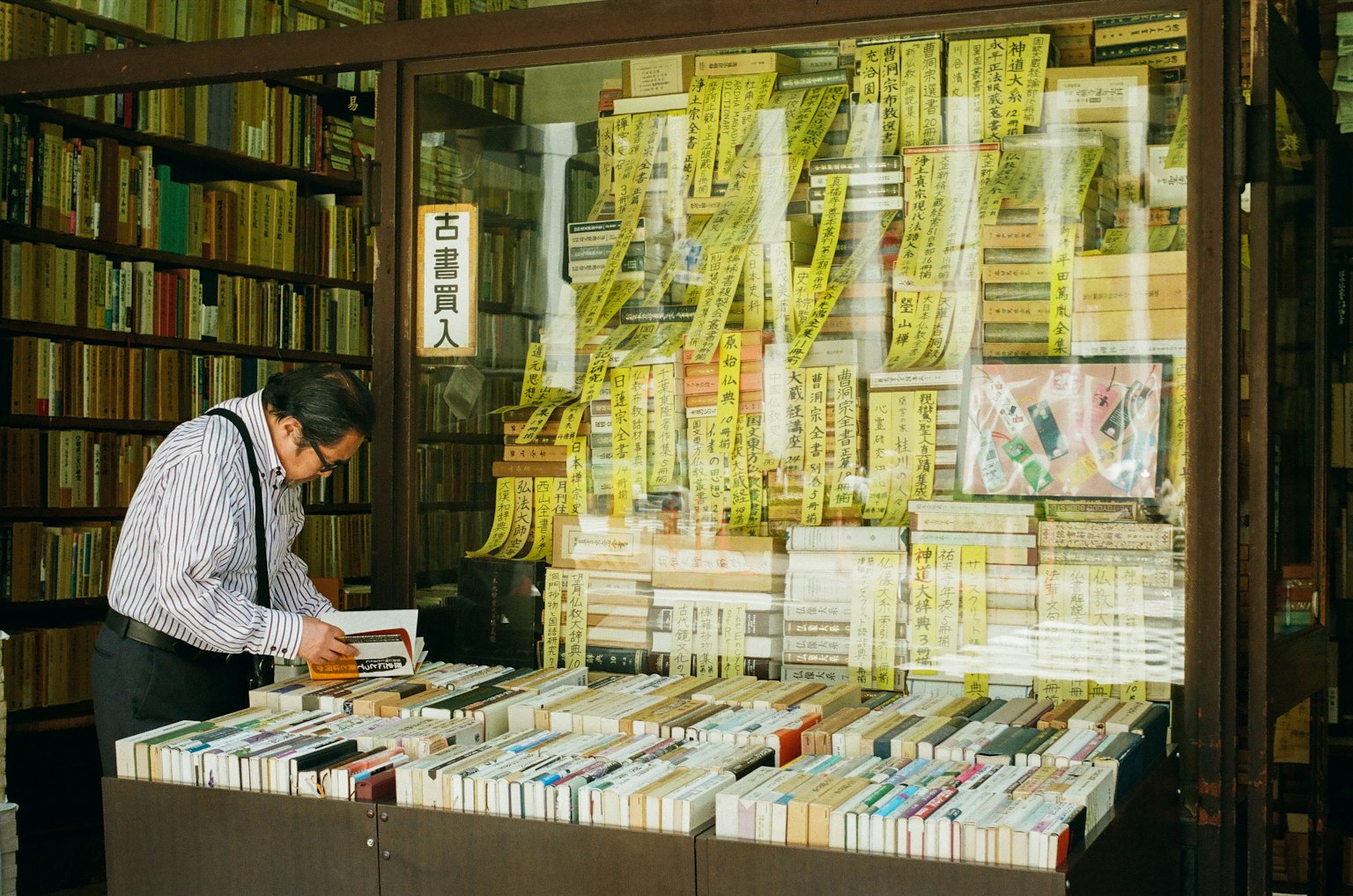 A man browsing books in a used bookstore with numerous books on display