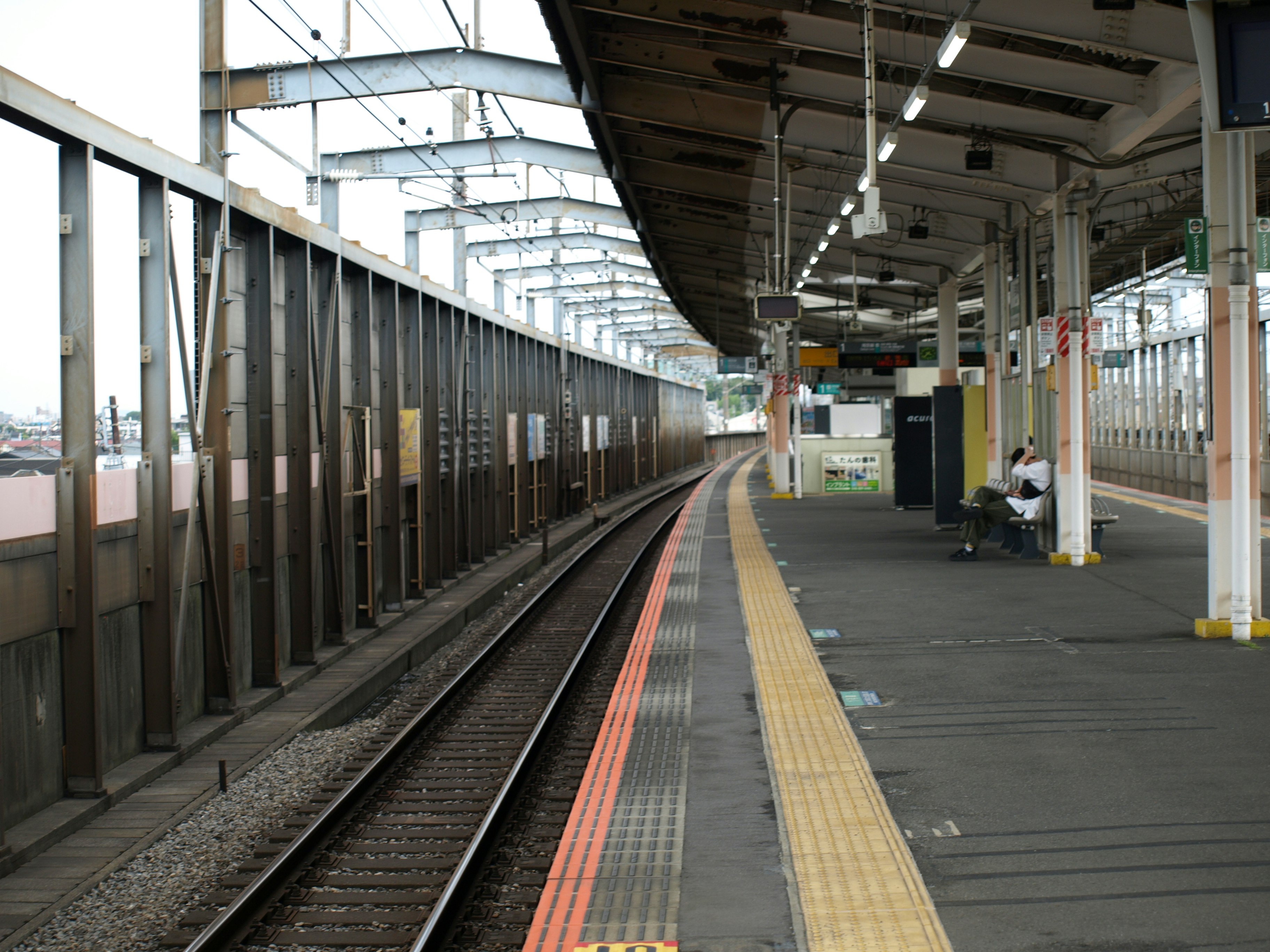 ホームの線路と黄色い点字ブロックのある駅の通路