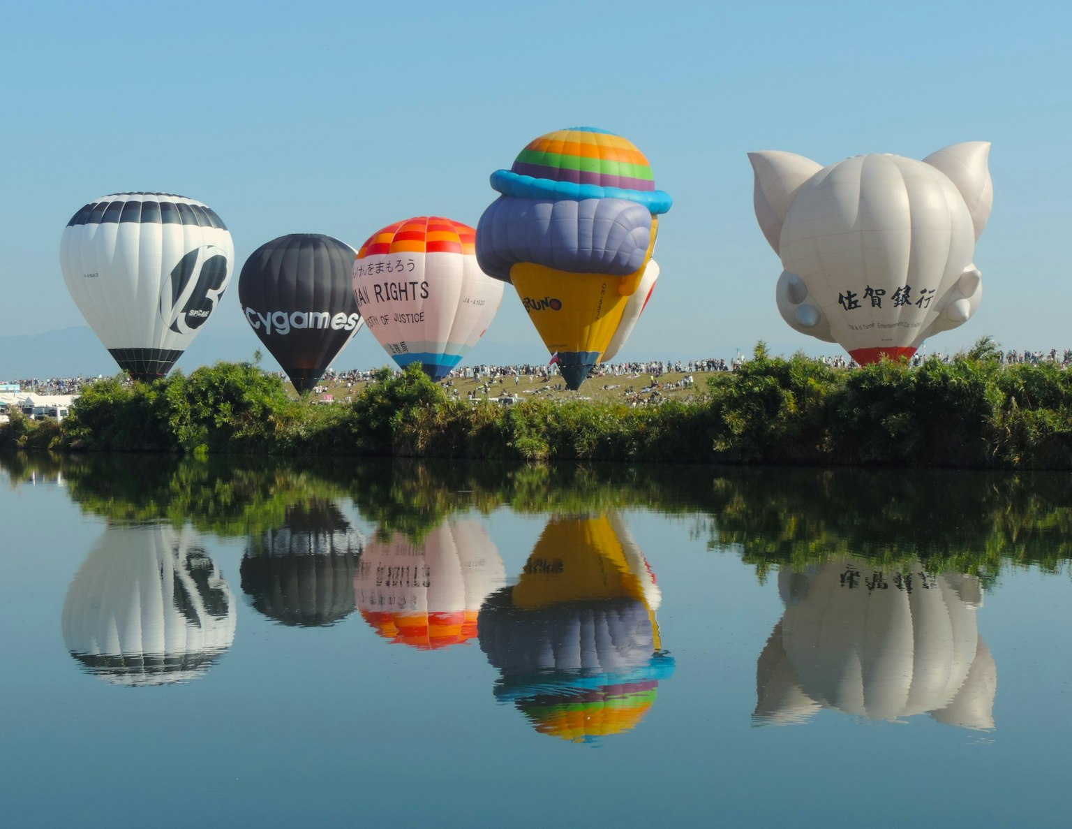 Colorful hot air balloons reflecting on a lake