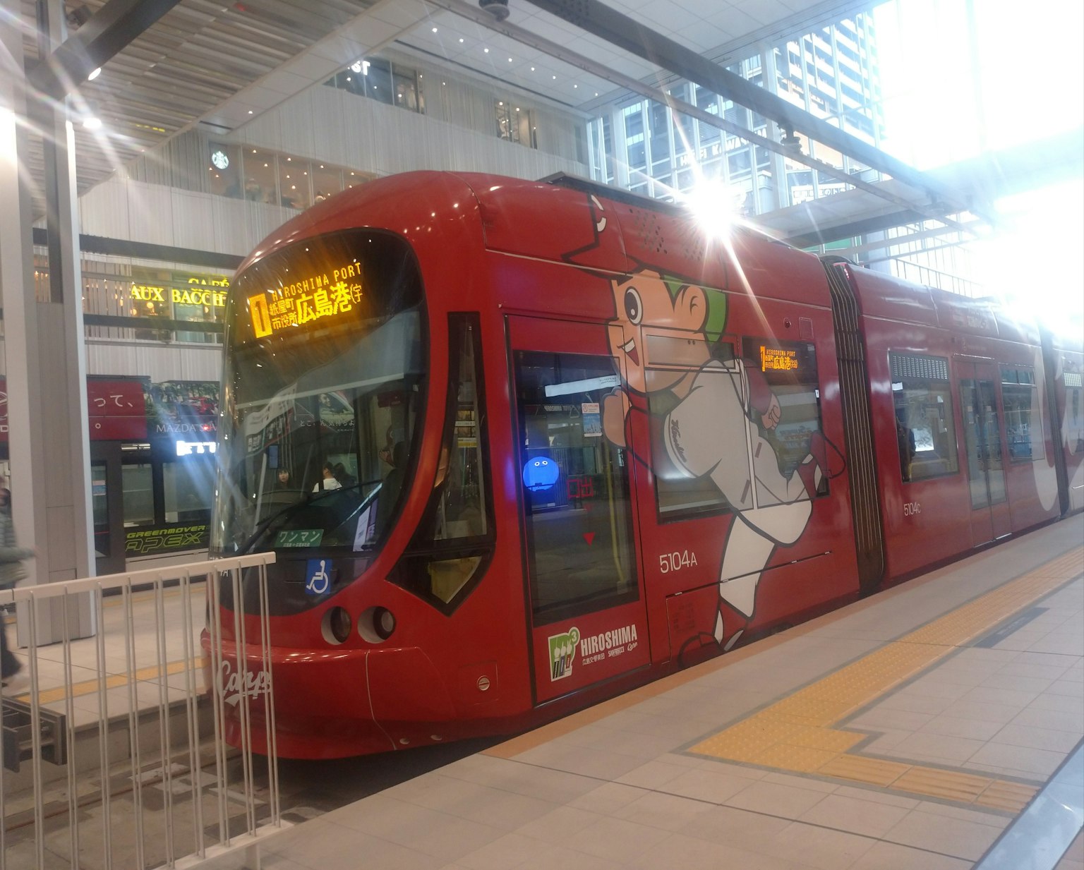 赤いトラムが駅に停車しているイメージでキャラクターの絵が描かれている