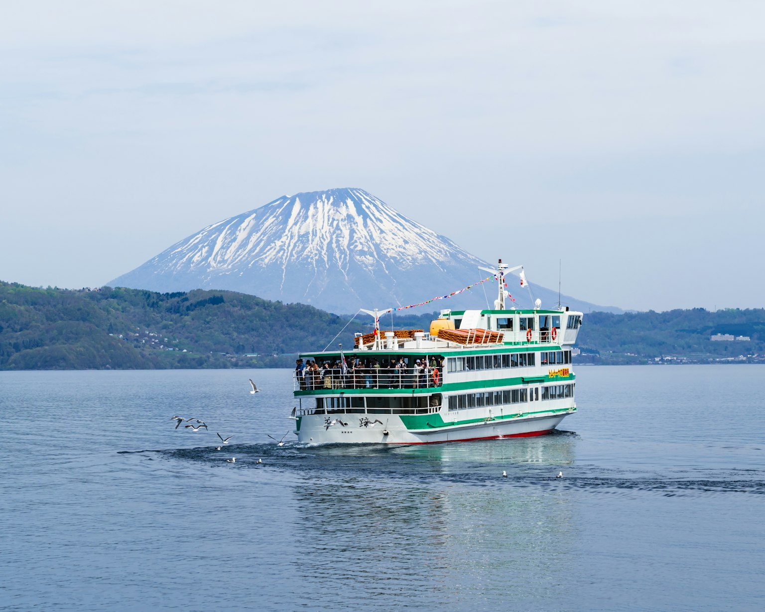 在湖上航行的旅游船和雪山