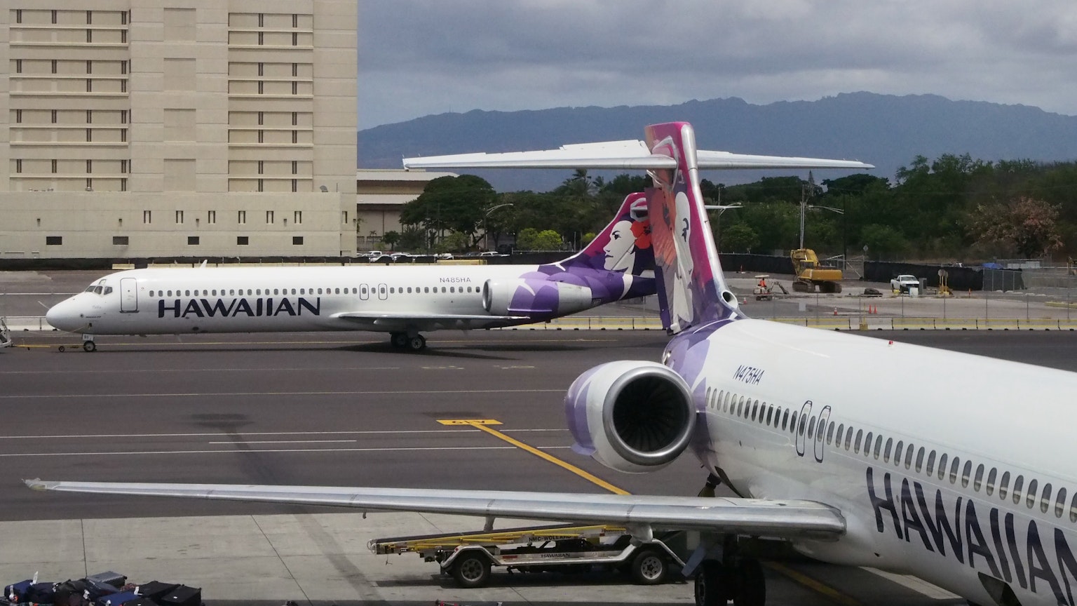 两架夏威夷航空的飞机在机场，背景有山