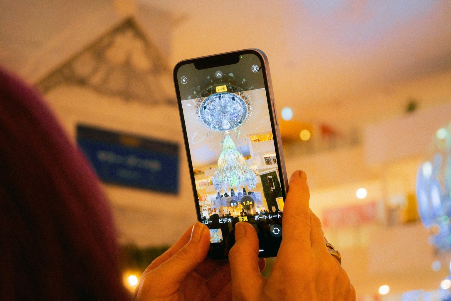 スマートフォンでシャンデリアを撮影している手