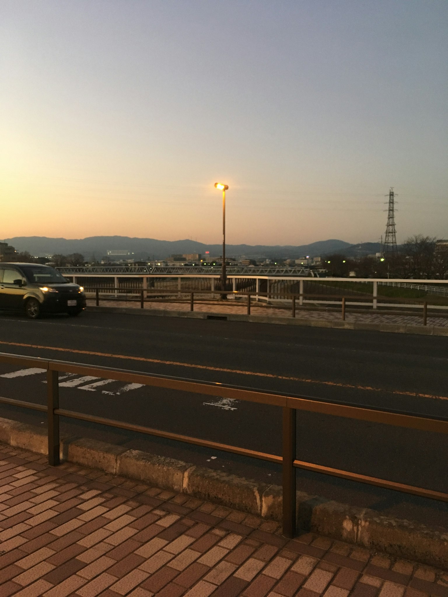 Scène de crépuscule d'une route avec un lampadaire et des montagnes visibles