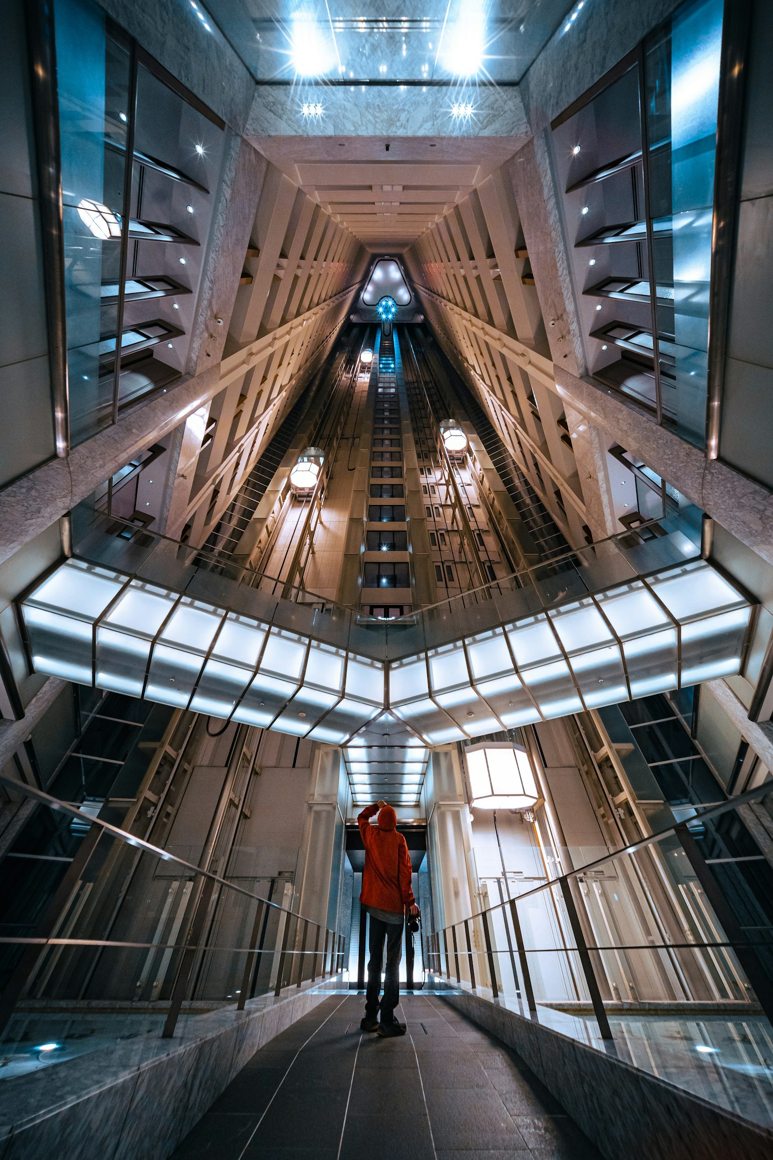 Eine Person steht in einem futuristischen Aufzugsschacht mit geometrischer Architektur