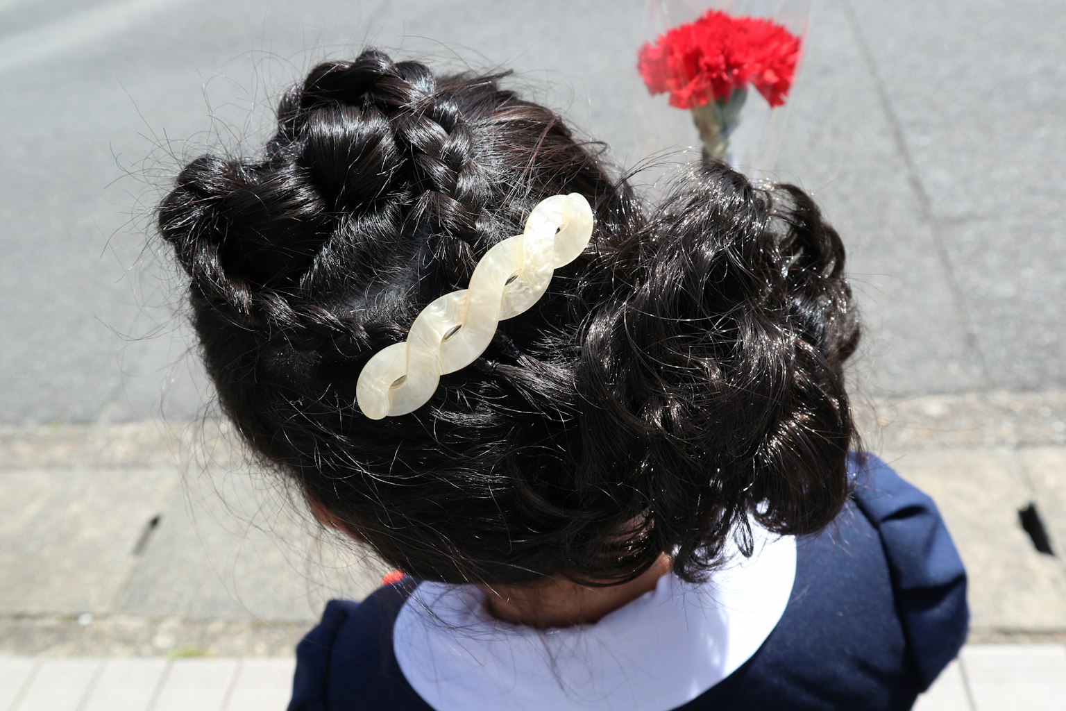 Bambina con capelli neri ricci adornati con un accessorio bianco per capelli