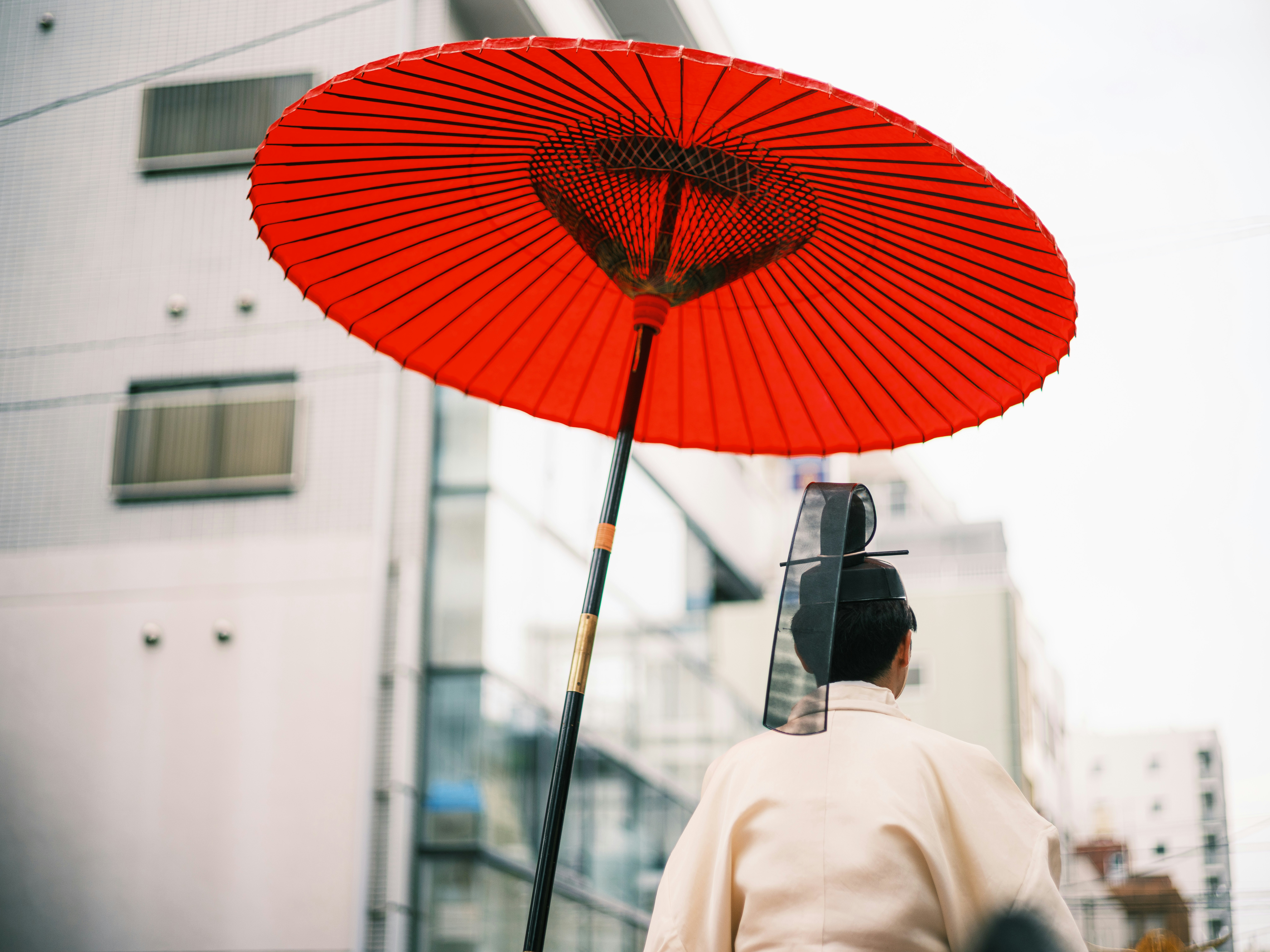 personne tenant un parapluie rouge dans une rue urbaine