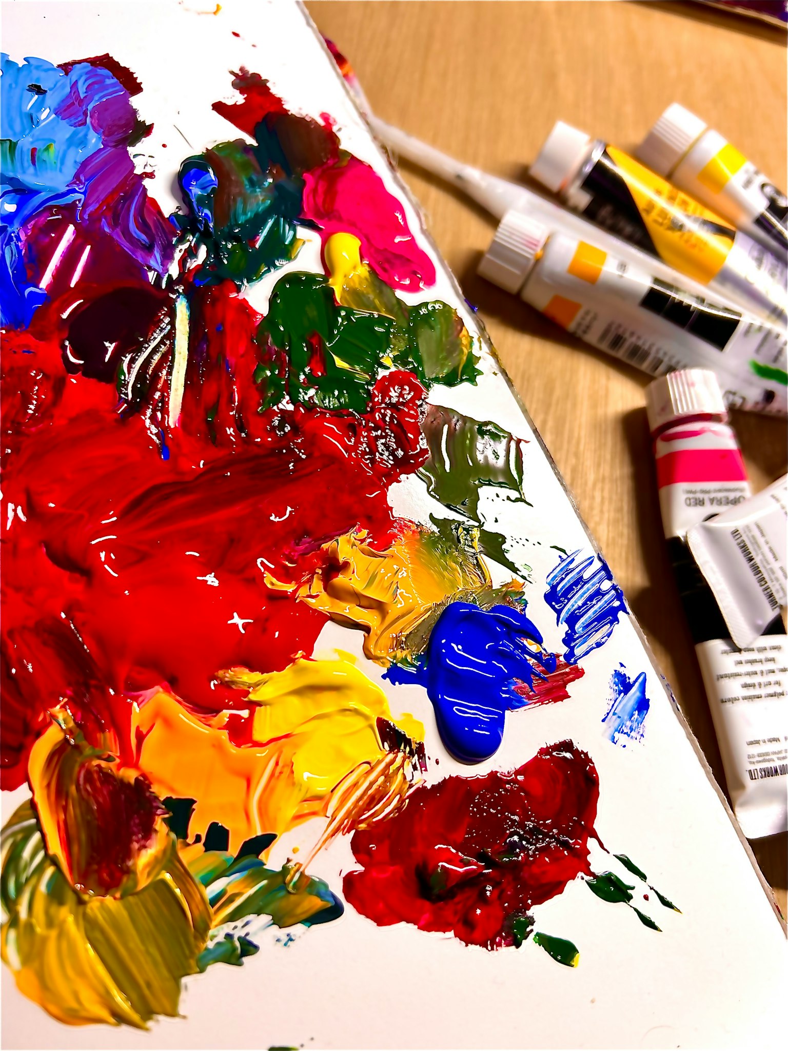 Colorful paint palette with mixed vibrant colors and surrounding paint tubes