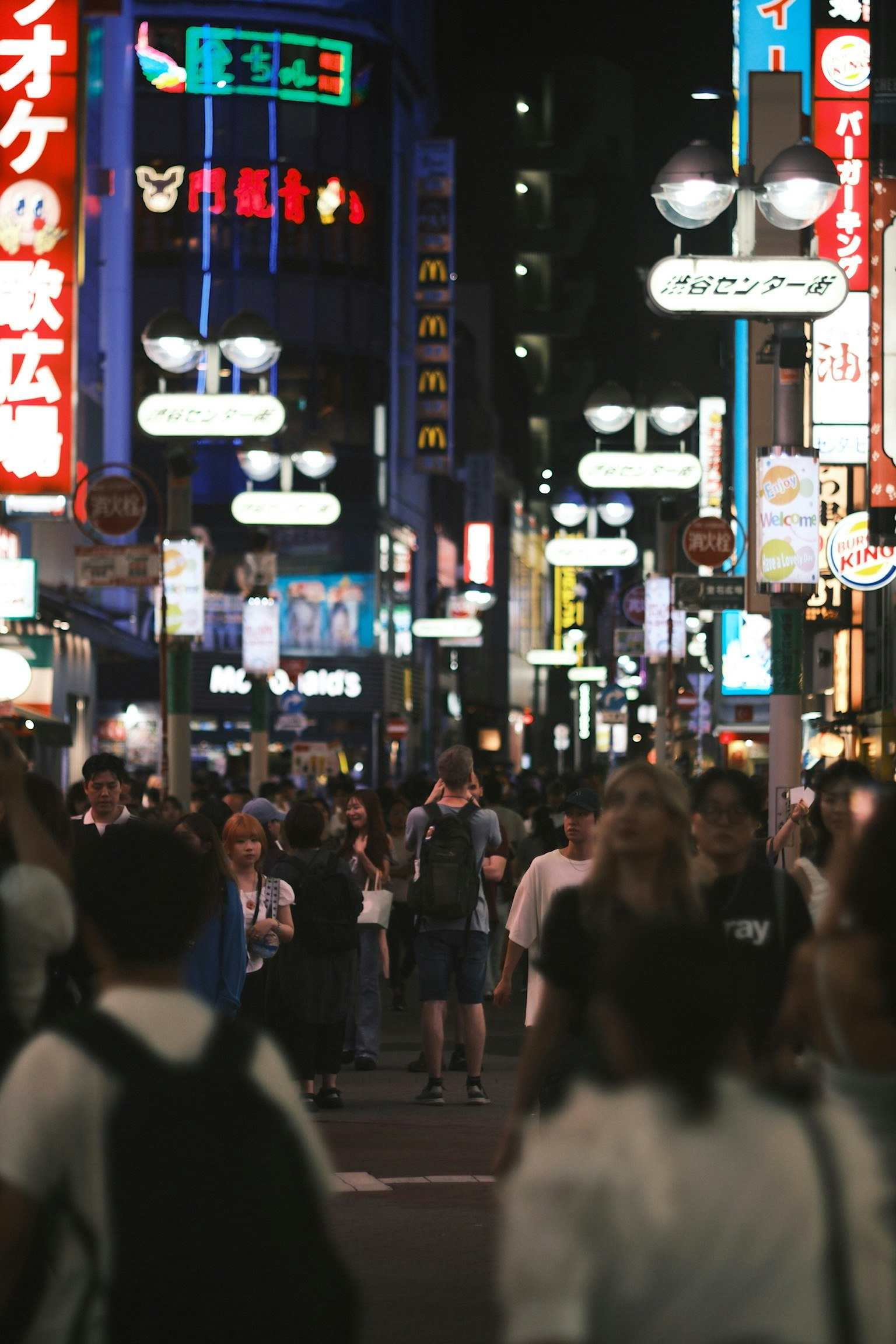 ฝูงชนในถนนยามค่ำคืนที่มีชีวิตชีวาพร้อมป้ายไฟนีออนหลากสี