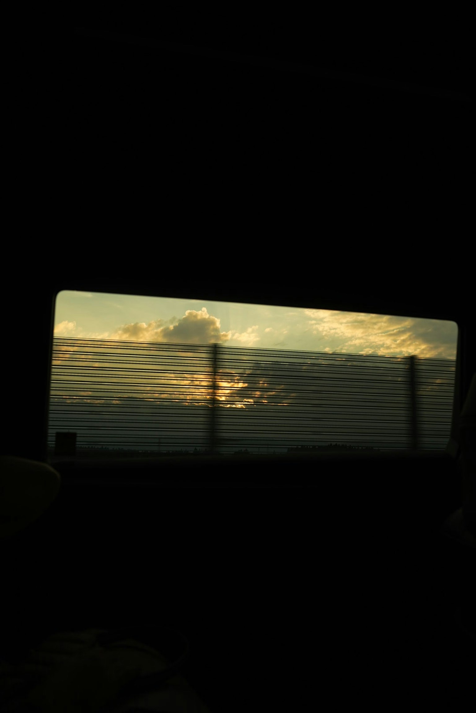 車の窓から見える夕焼けの空と雲