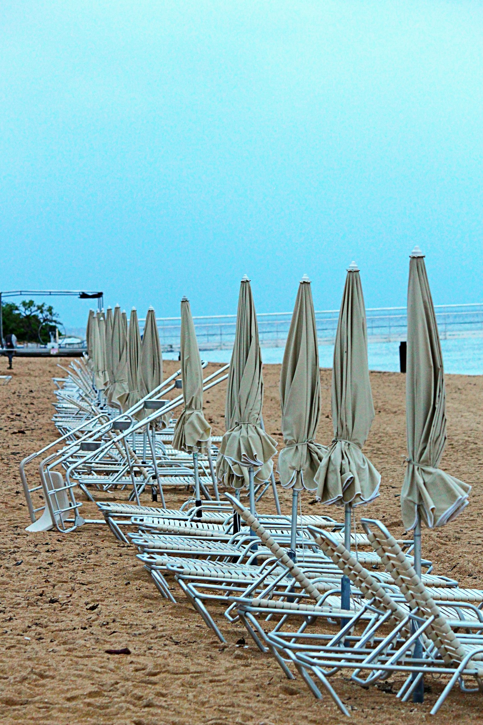Vista di spiaggia con ombrelloni bianchi e lettini allineati