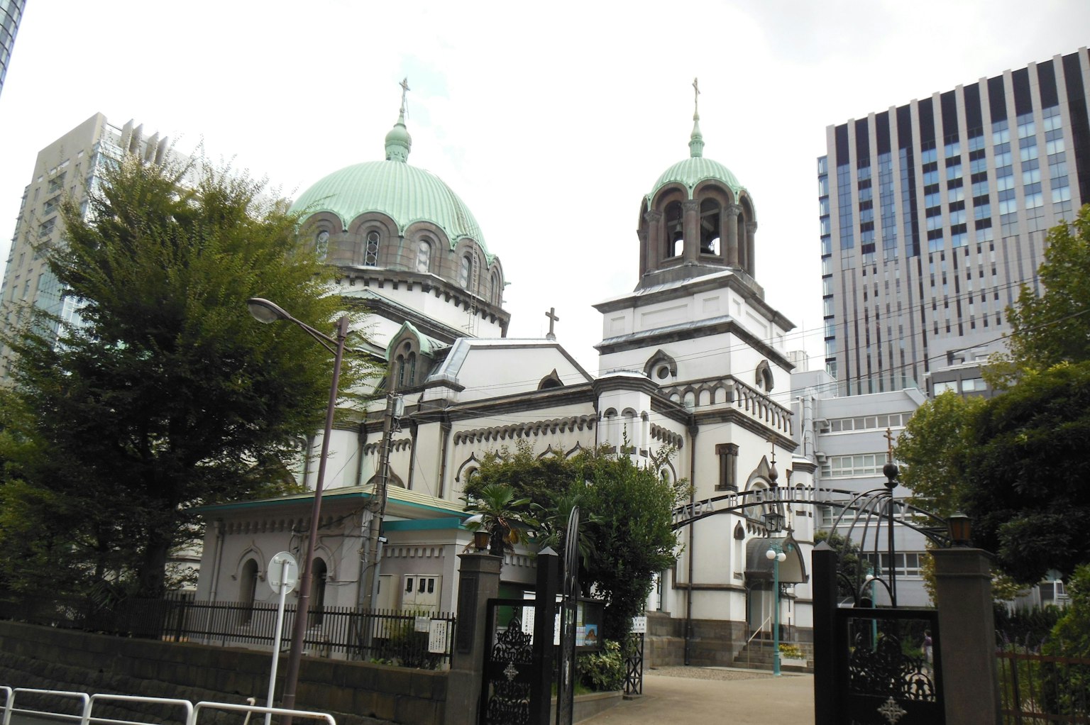 Gereja bersejarah dengan kubah hijau di samping gedung pencakar langit modern