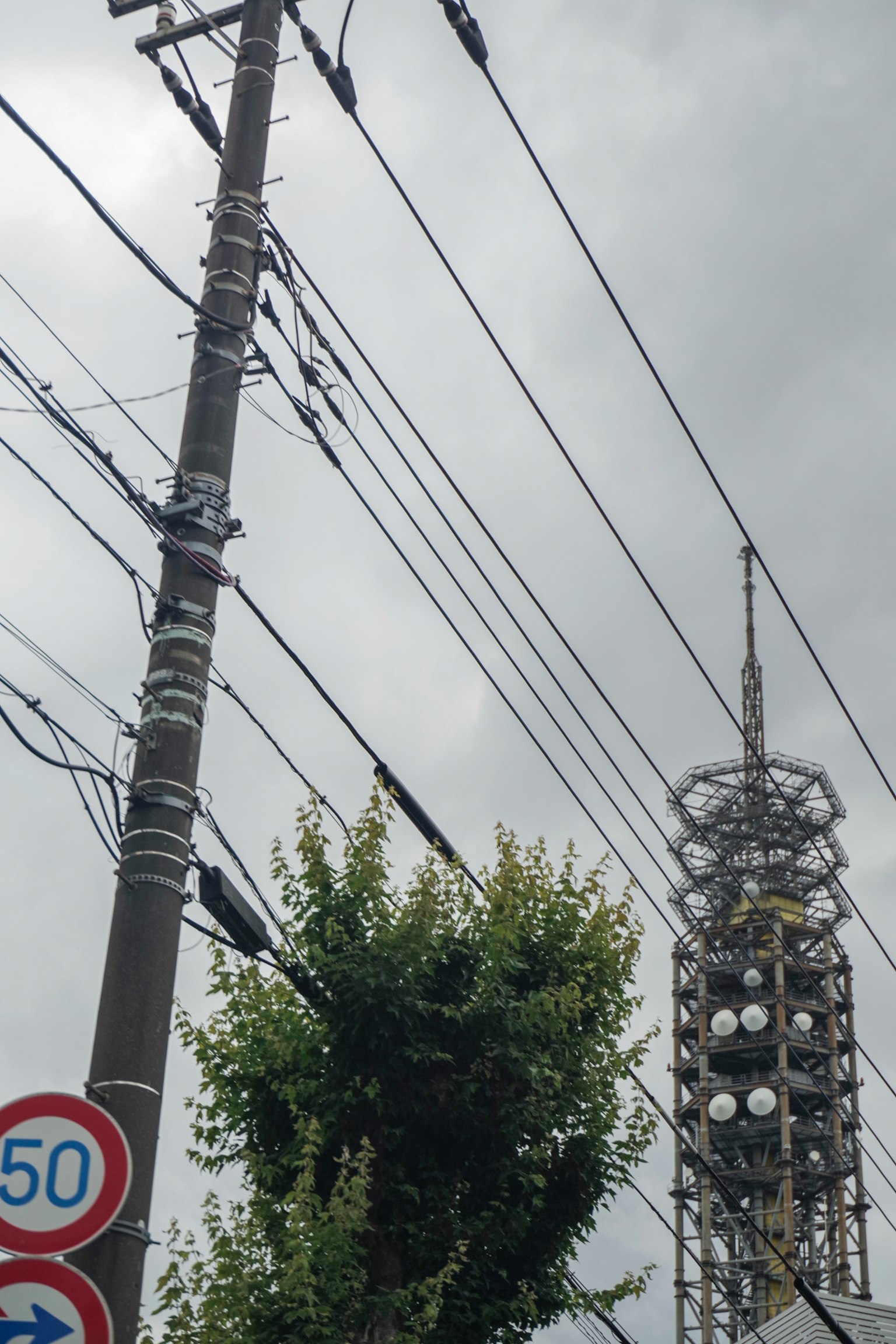 Vue d'un poteau électrique et d'une tour de communication sous un ciel nuageux