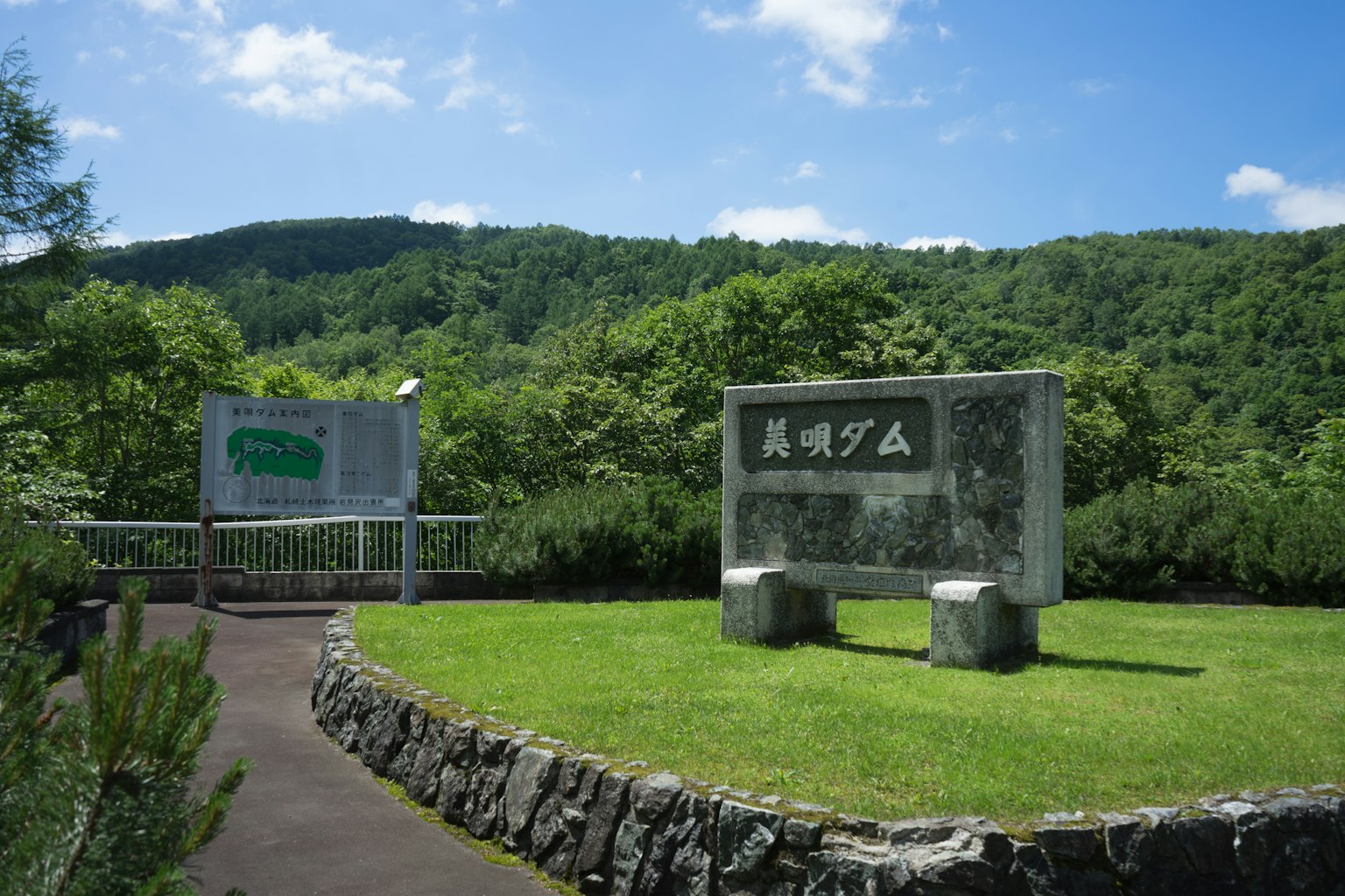 Ingresso del parco con monumenti di pietra e montagne verdi sullo sfondo
