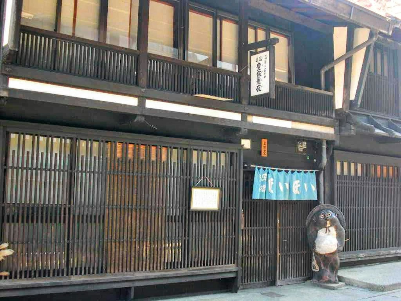 Außenansicht eines traditionellen japanischen Stadthauses schwarze Holzstruktur vertikale Lamellenfenster blauer Vorhang