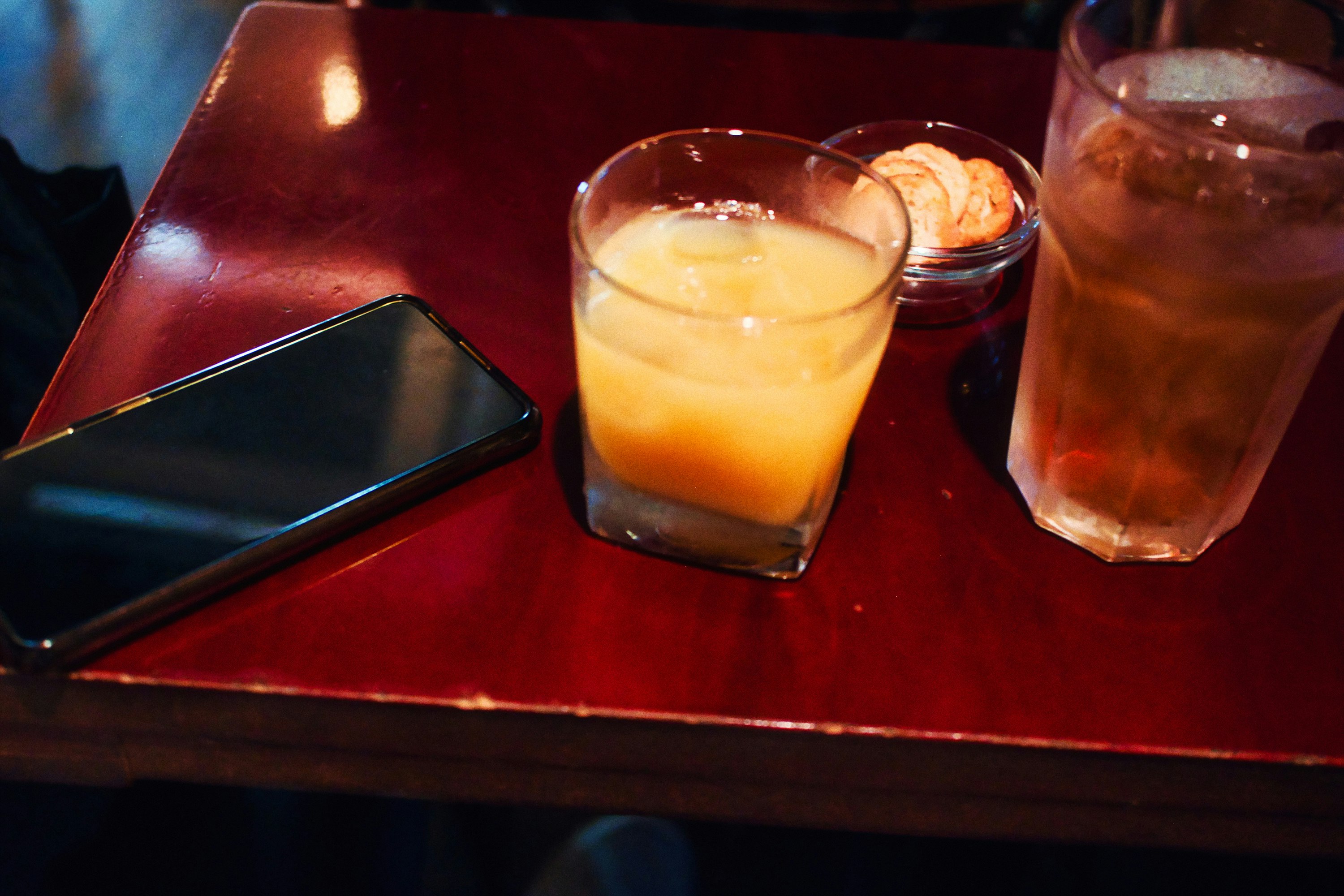 glasses and a smartphone on a red table, after work break