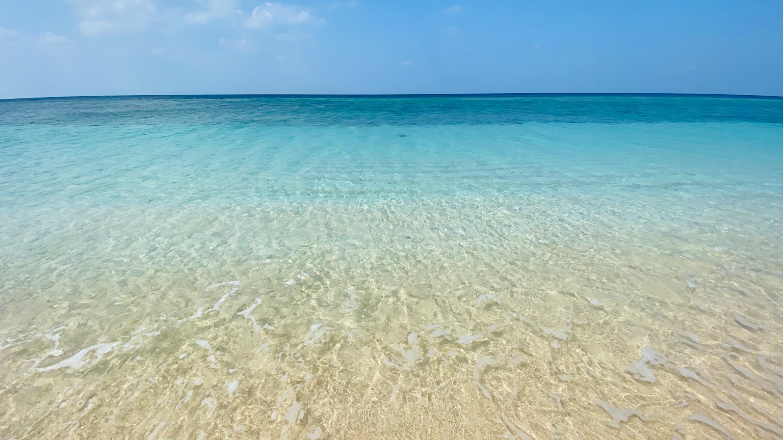 Pemandangan laut biru jernih dengan pantai berpasir