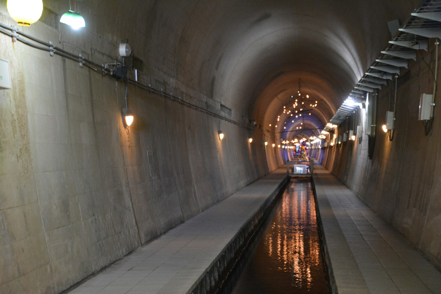 Interno di un tunnel con un canale d'acqua e illuminazione a parete