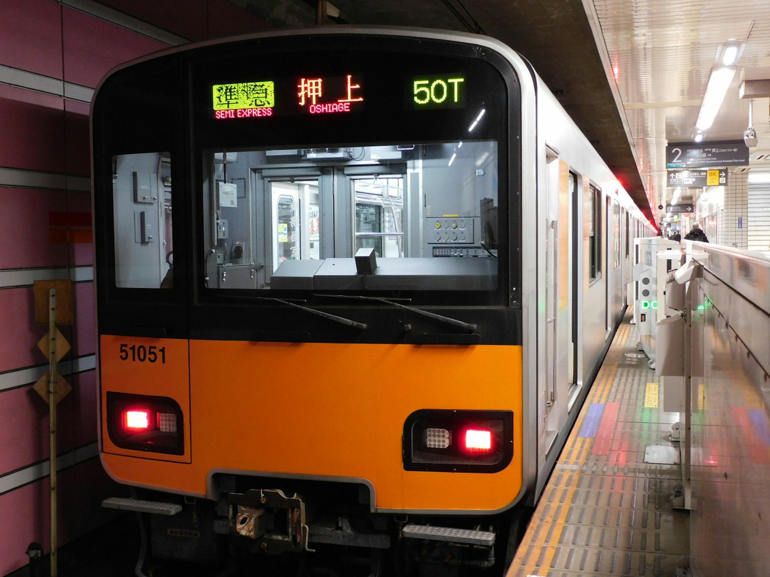 Un train orange et noir est arrêté à une station