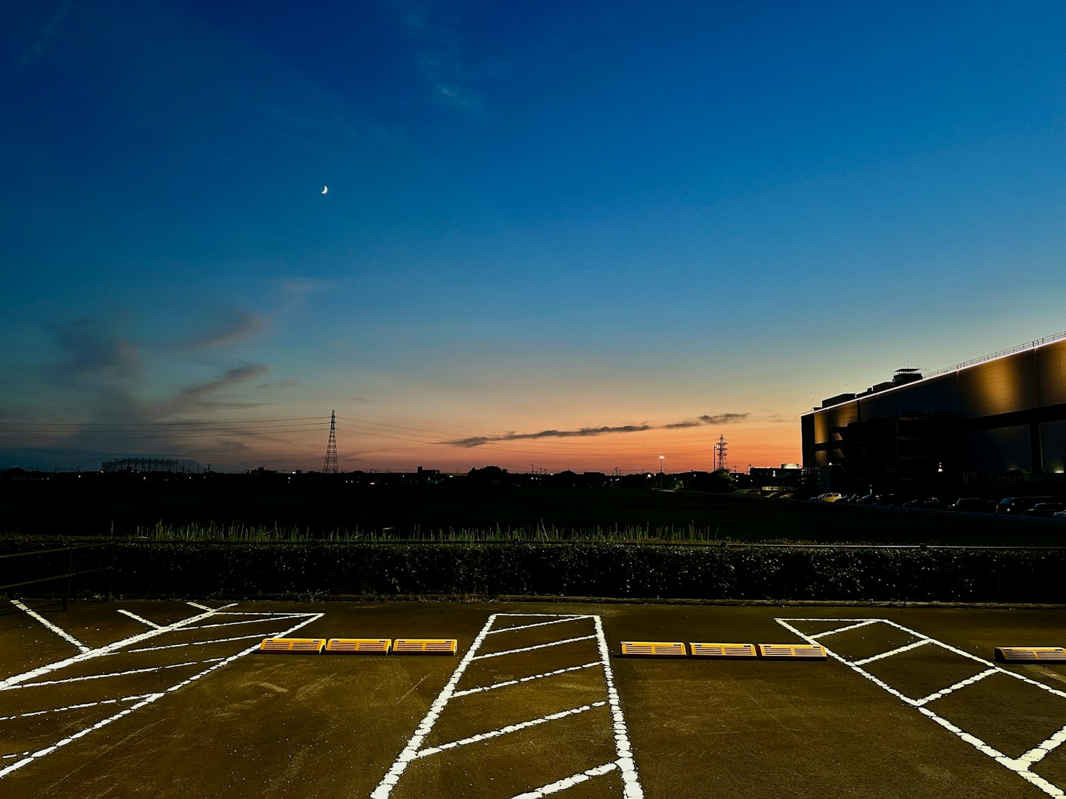 Ciel crépusculaire avec des lignes de stationnement blanches et la silhouette d'un bâtiment