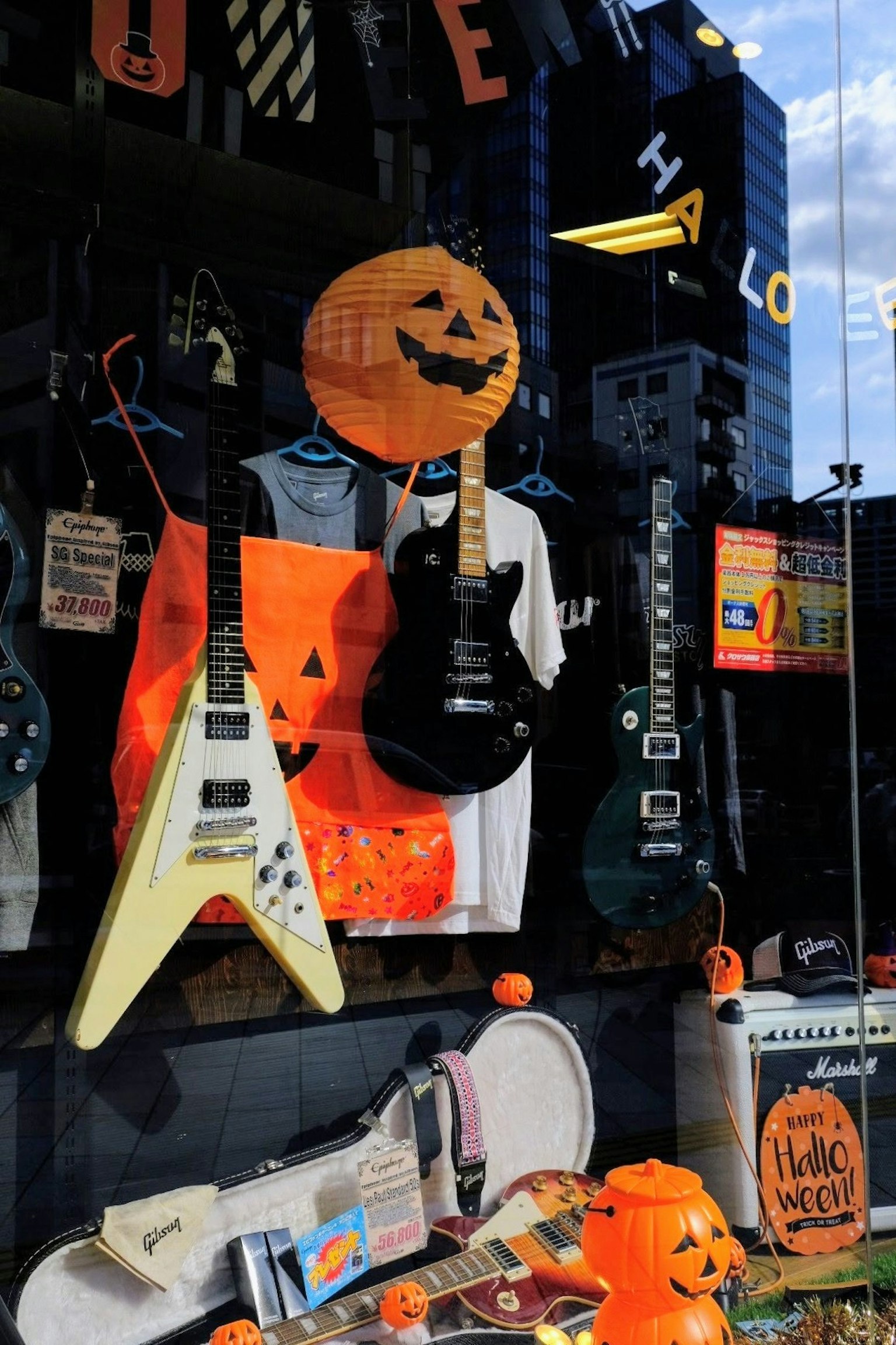 Schaufenster eines Musikgeschäfts, das für Halloween dekoriert ist, mit Gitarren und orangen Akzenten